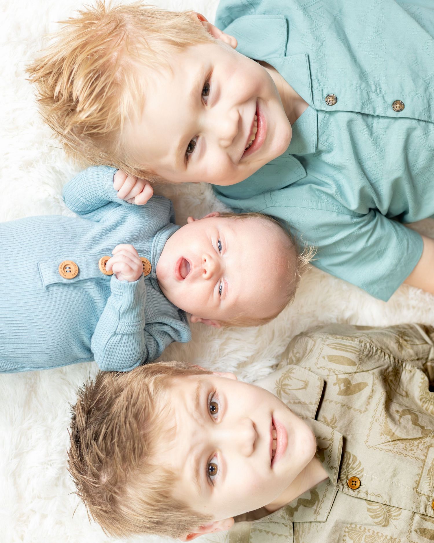 three brothers on white blanket looking up