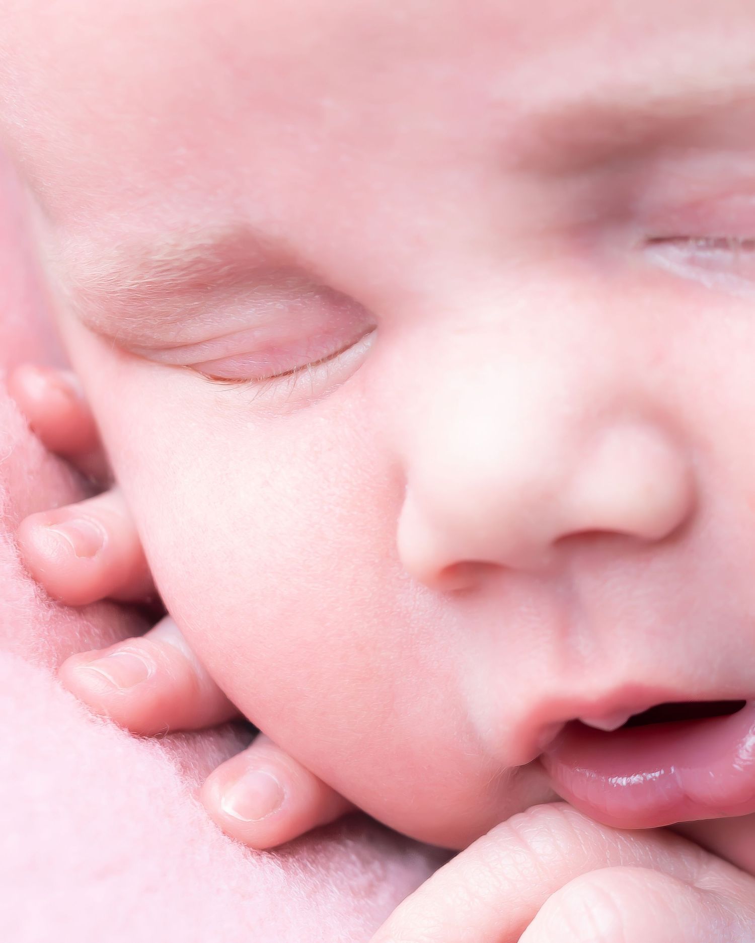 A close-up panoramic series of soft baby features showing delicate nose, lips and skin details in pink tones.