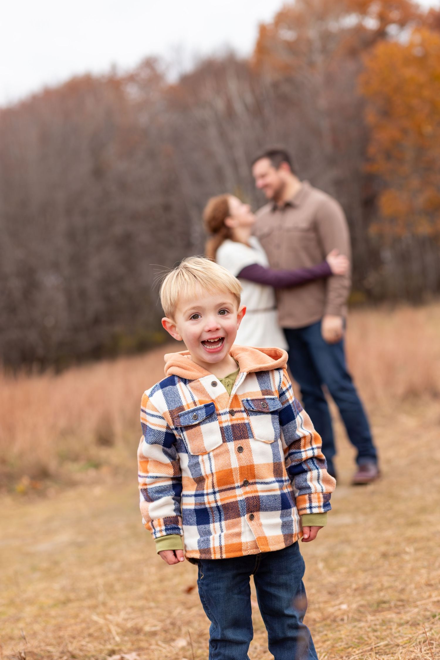 A child in a plaid flannel shirt and jeans runs playfully through a golden autumn field.