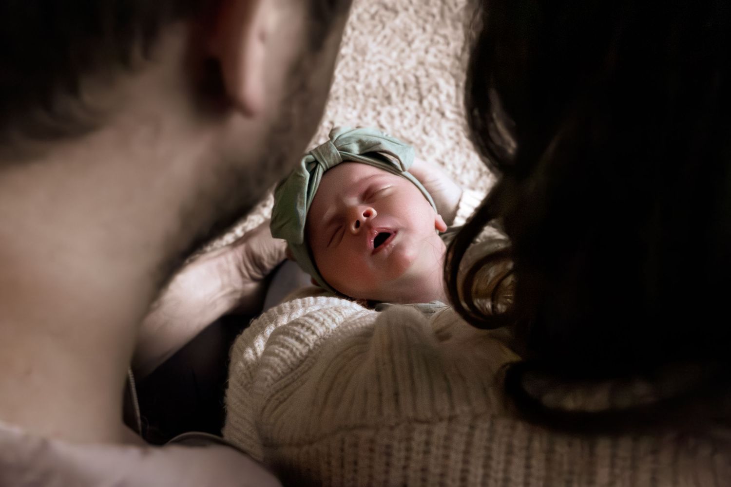 A peaceful sleeping baby lies on soft beige bedding in a serene natural light setting.
