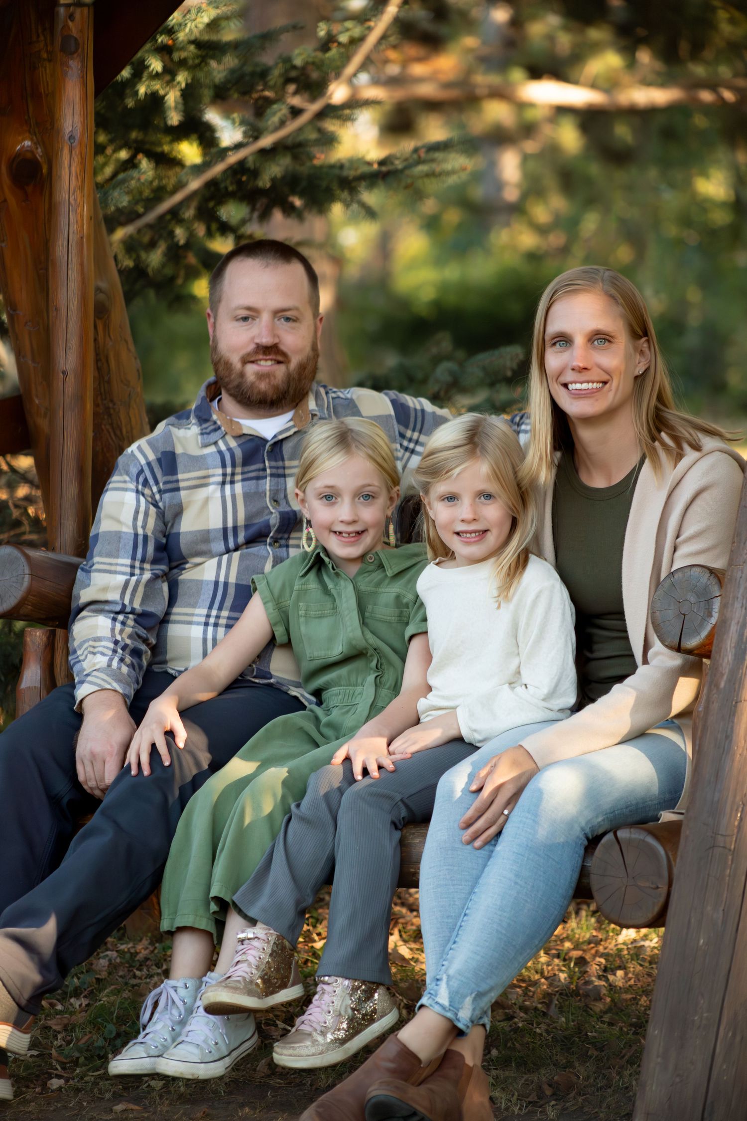 Family relaxing together on wooden bench during fall photo session.