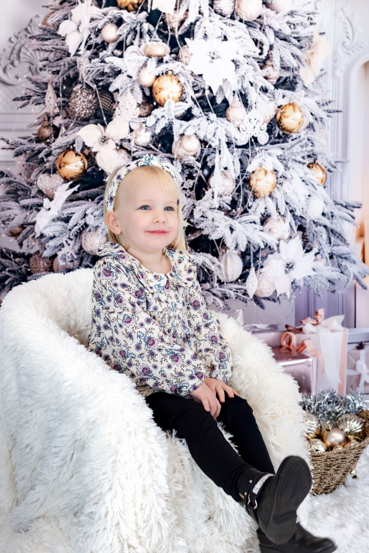 A flocked white Christmas tree decorated with silver and gold ornaments serves as a festive holiday backdrop.