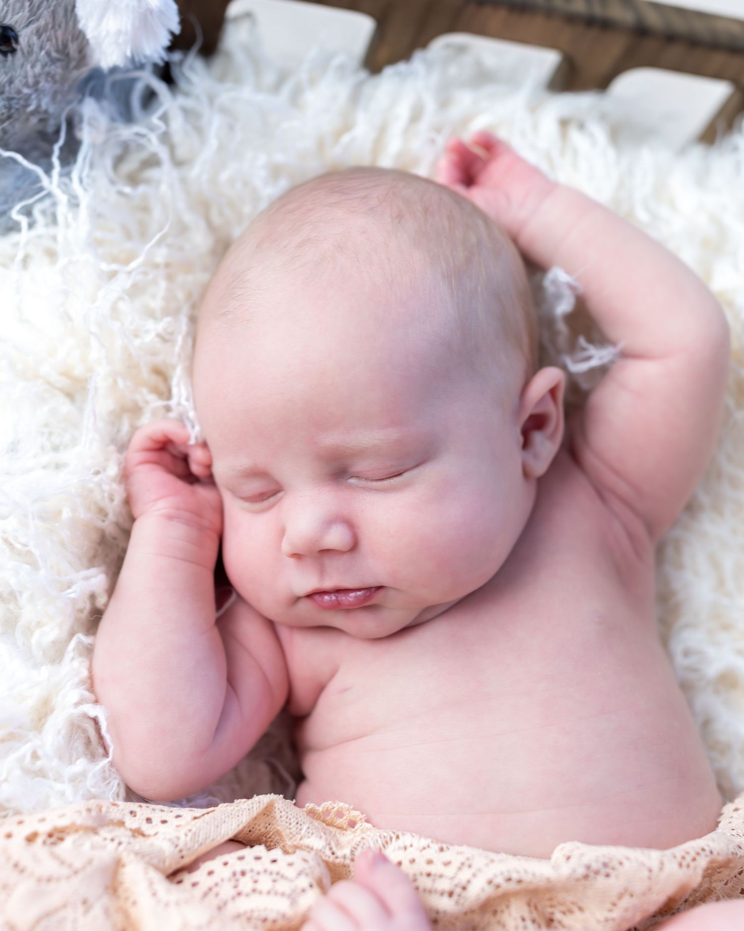 Sleeping infant resting peacefully on white fluffy blanket with lace trim.
