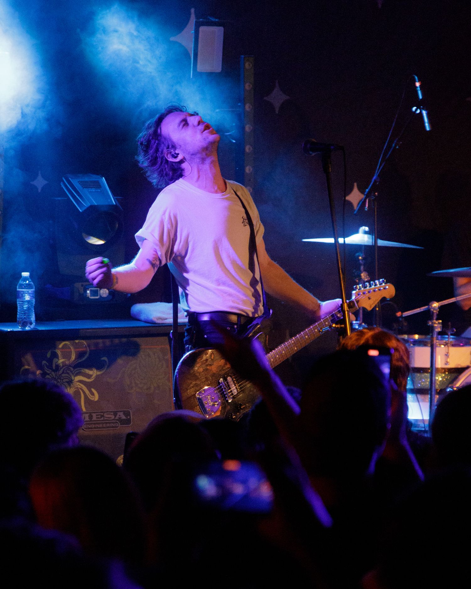 Band performs live show with dramatic blue smoke effects and stage lighting.
