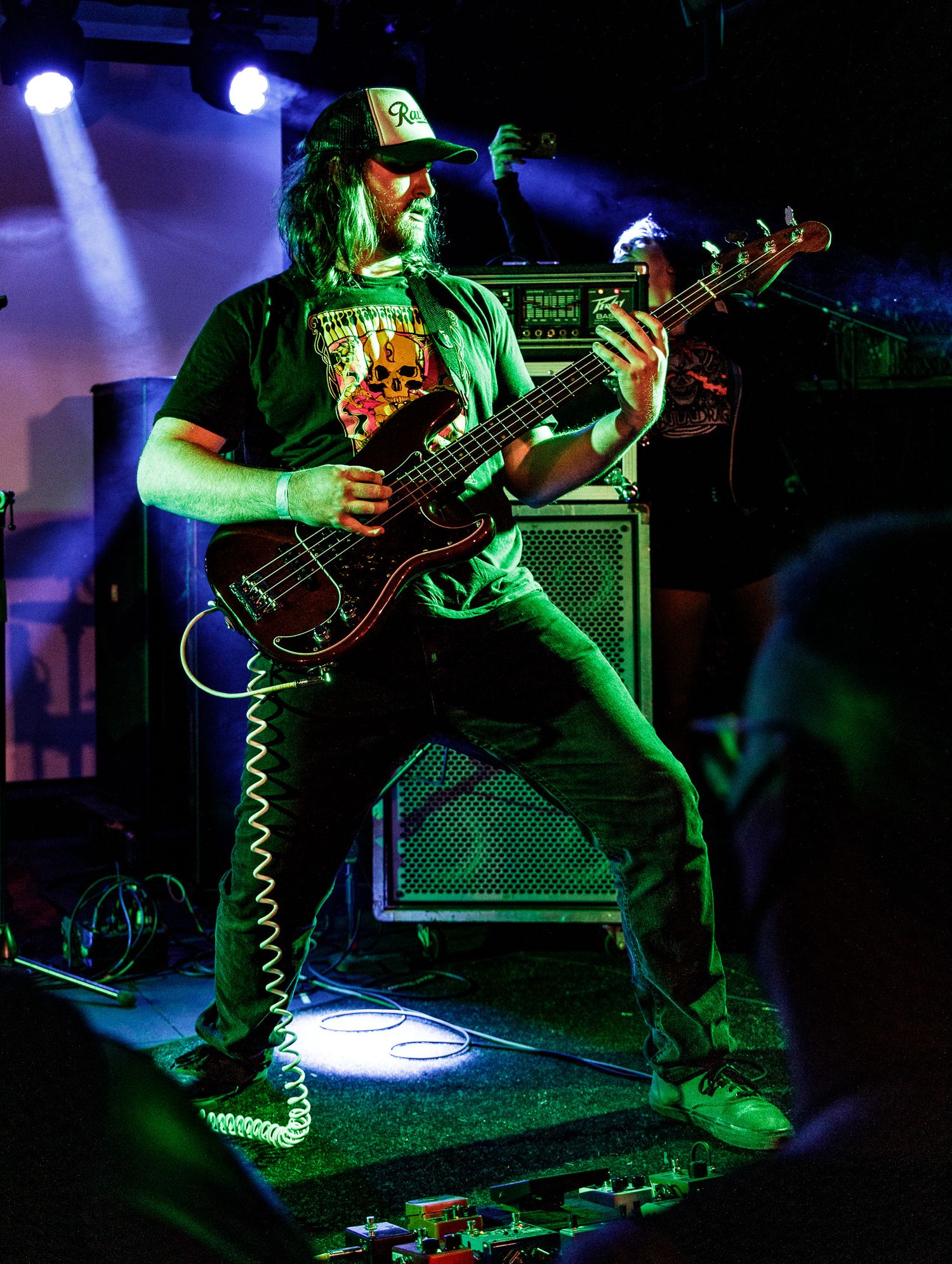 A guitarist performs on stage with amplifiers and moody lighting.