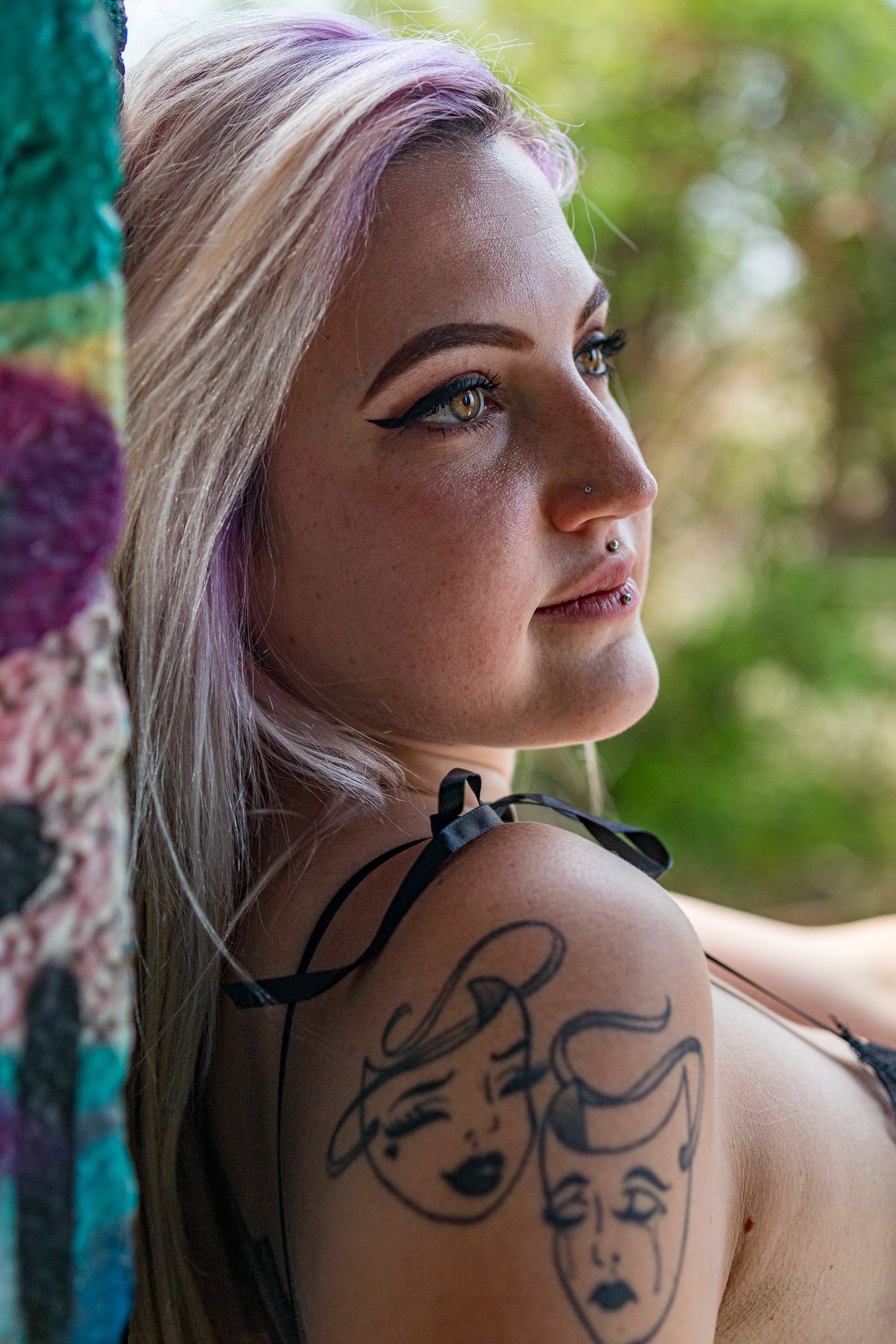 Artistic portrait series showing dramatic tattoo art on shoulder against natural outdoor lighting.