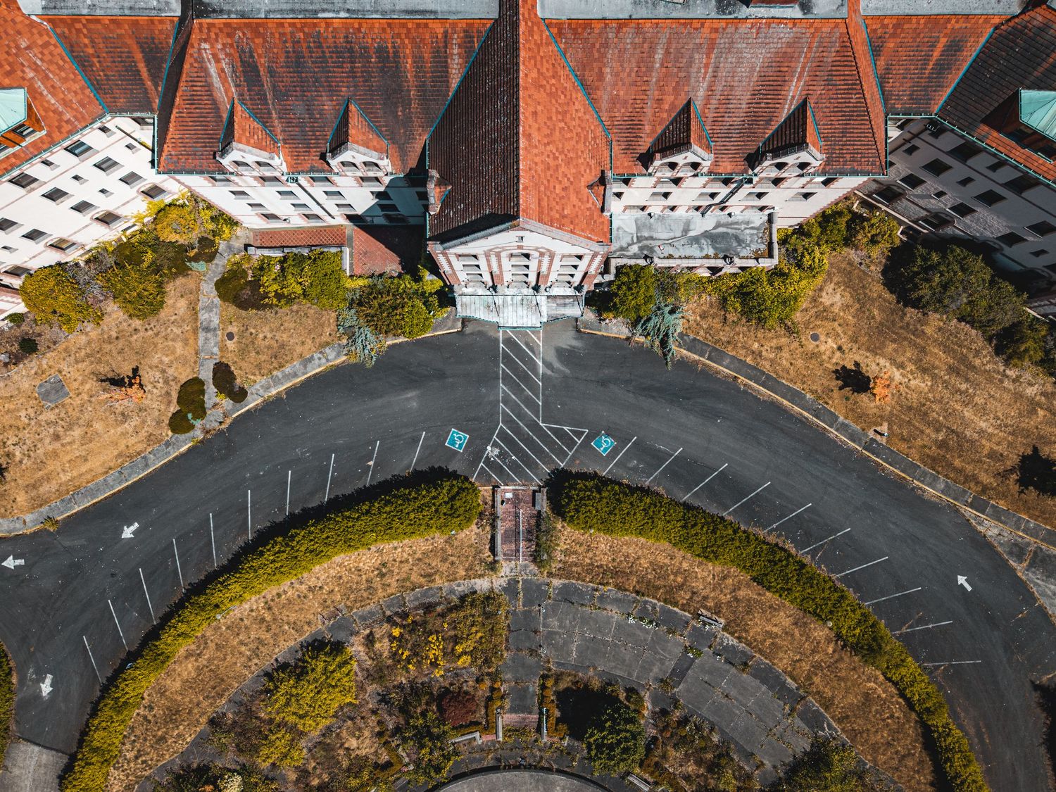 Drone view of curved driveway and landscaping leading to large institutional building complex.