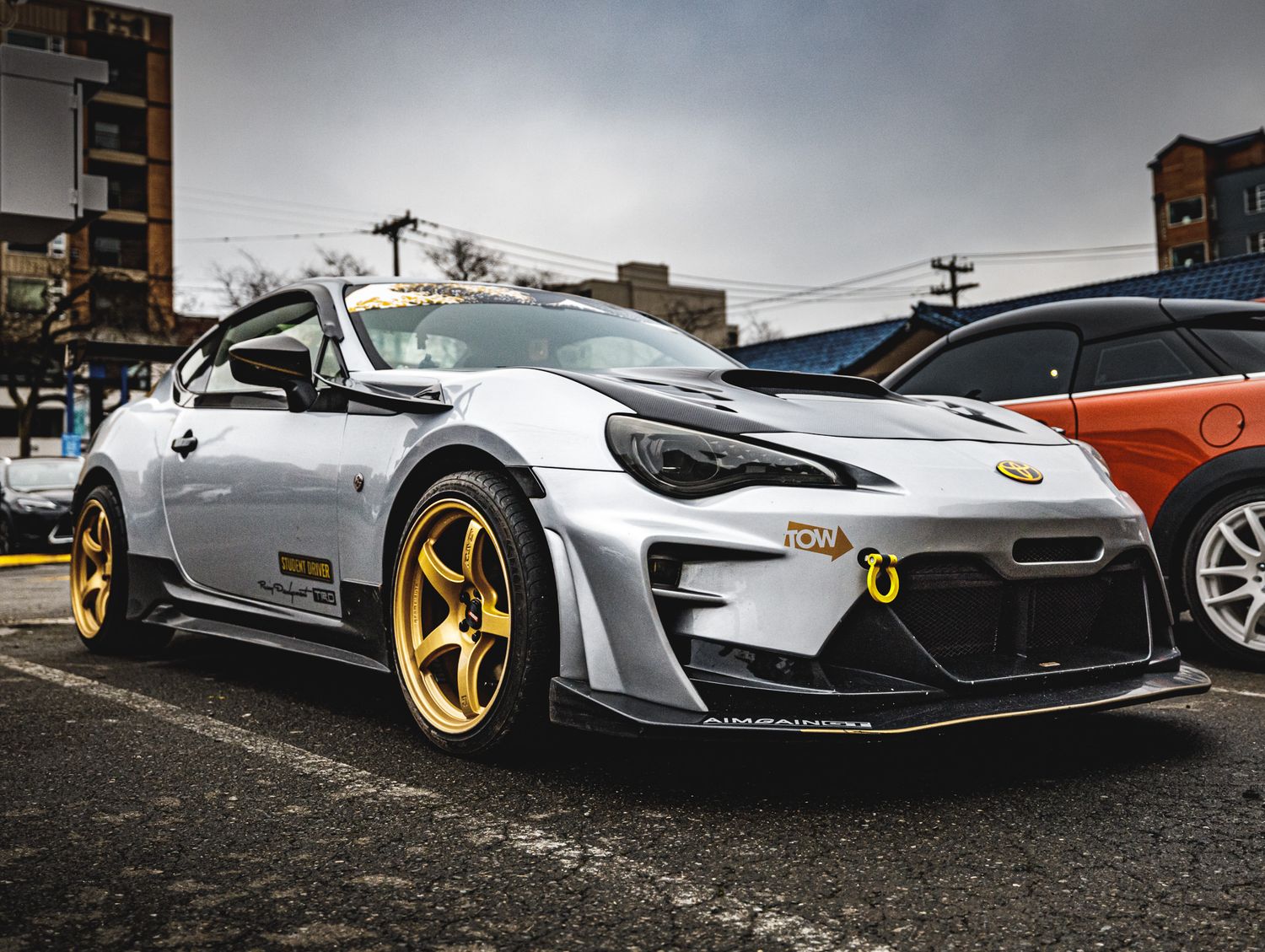 Side profile view of modern white sports cars with custom gold wheels parked in a row.