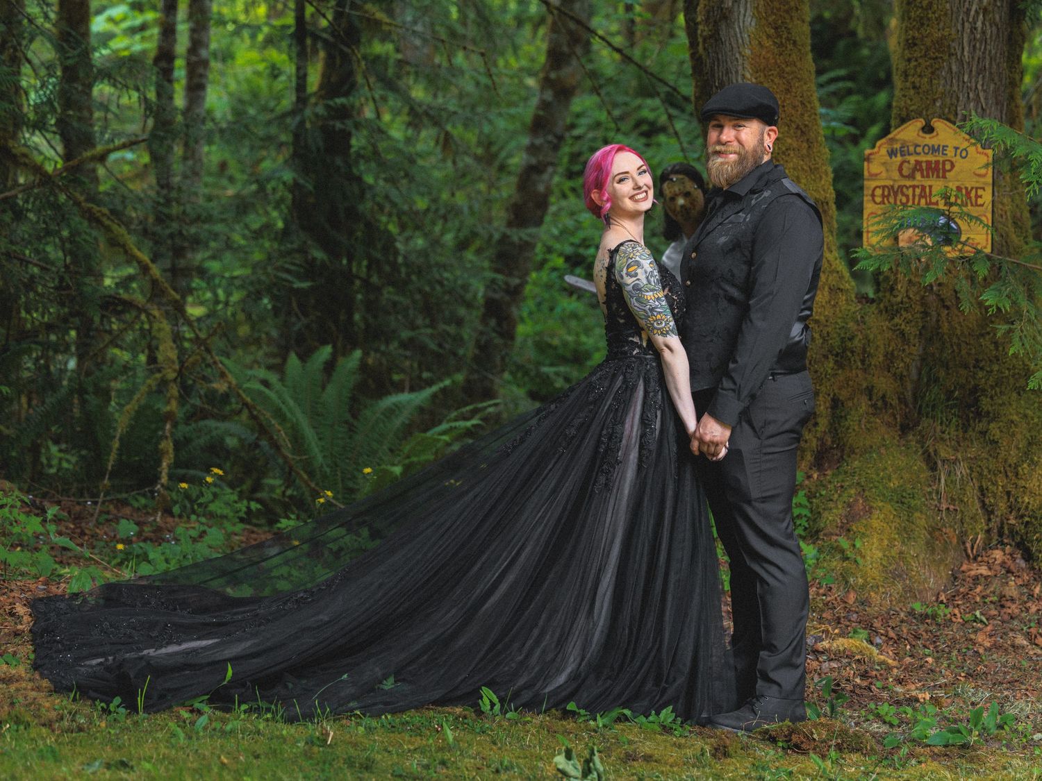 A dramatic black dress trails along a forest path during a photoshoot.