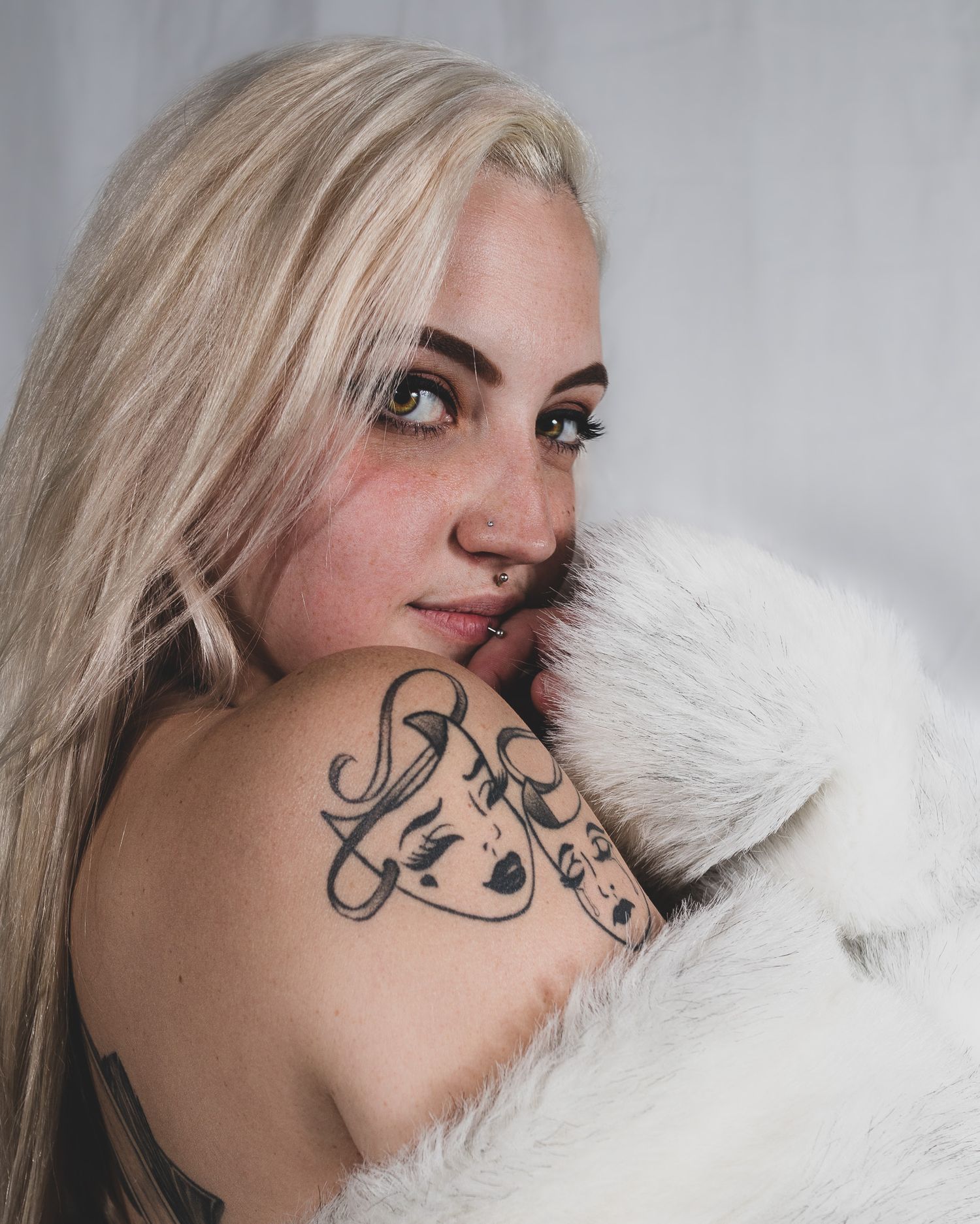 Elegant boudoir photography featuring shoulder tattoo art with white fur accent.