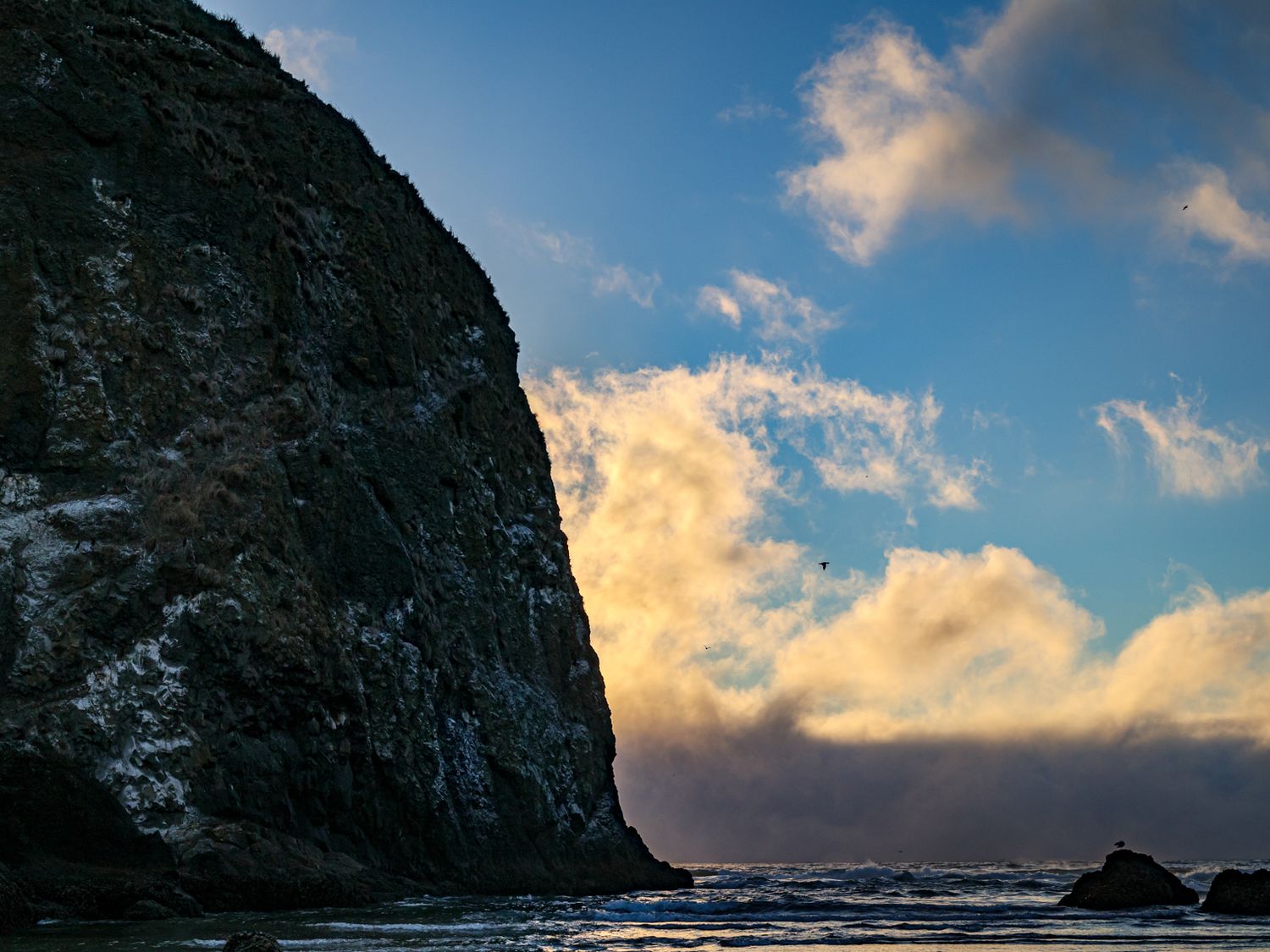Majestic rocky cliffs against a sunset sky with wispy clouds.