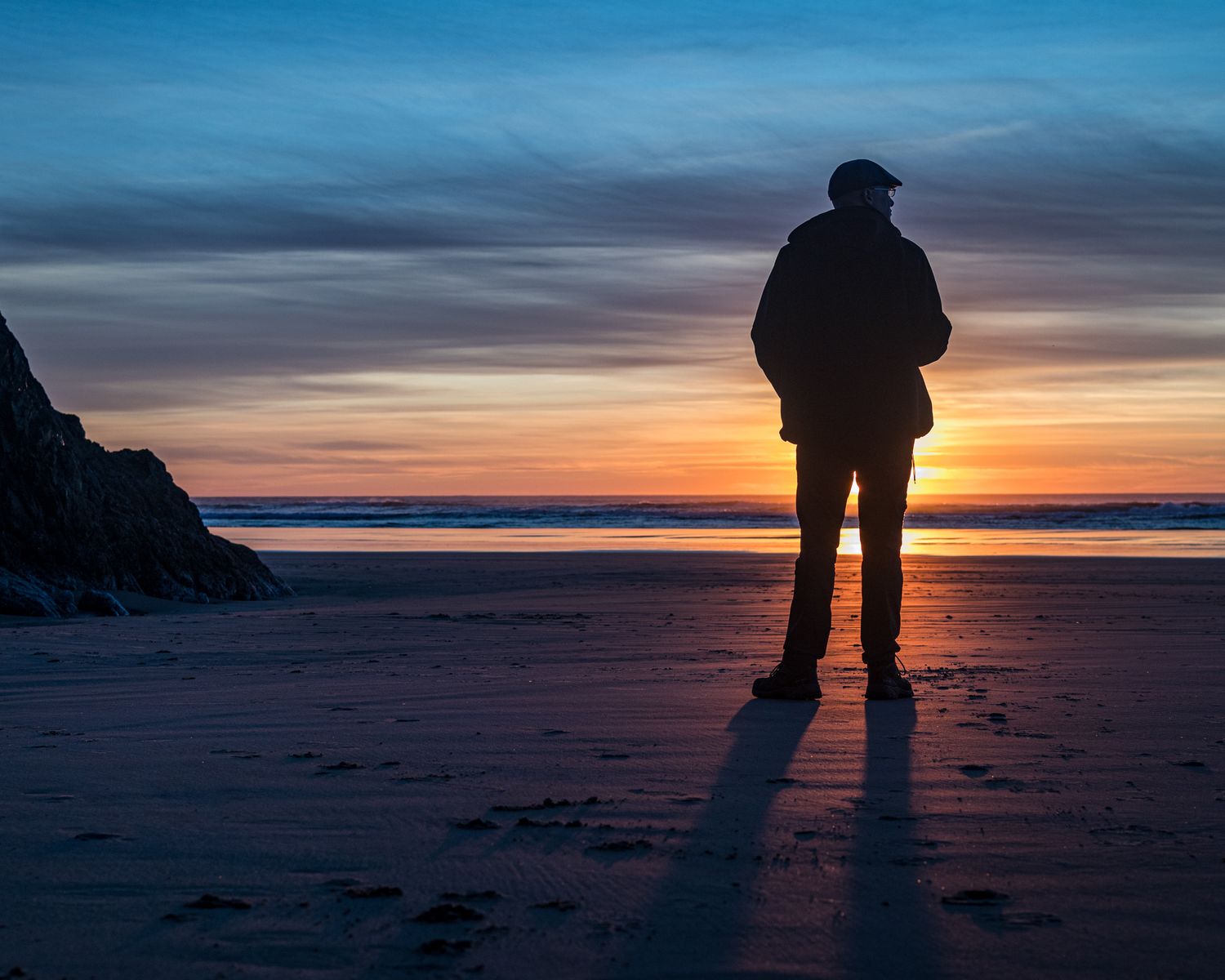 Silhouettes against a dramatic beach sunset with long shadows stretching across the sand.