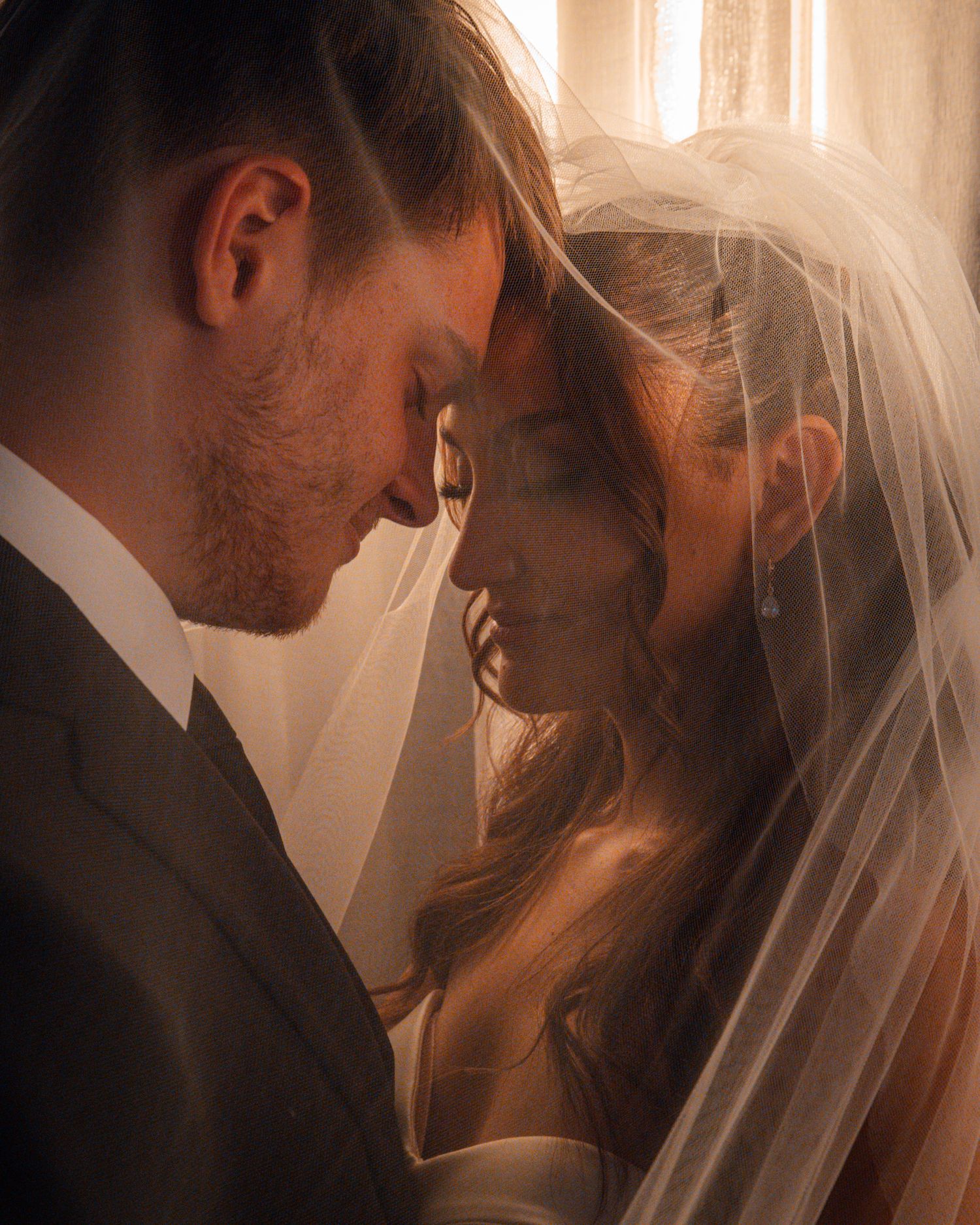Warm-toned intimate wedding portraits with soft lighting and delicate veil details.