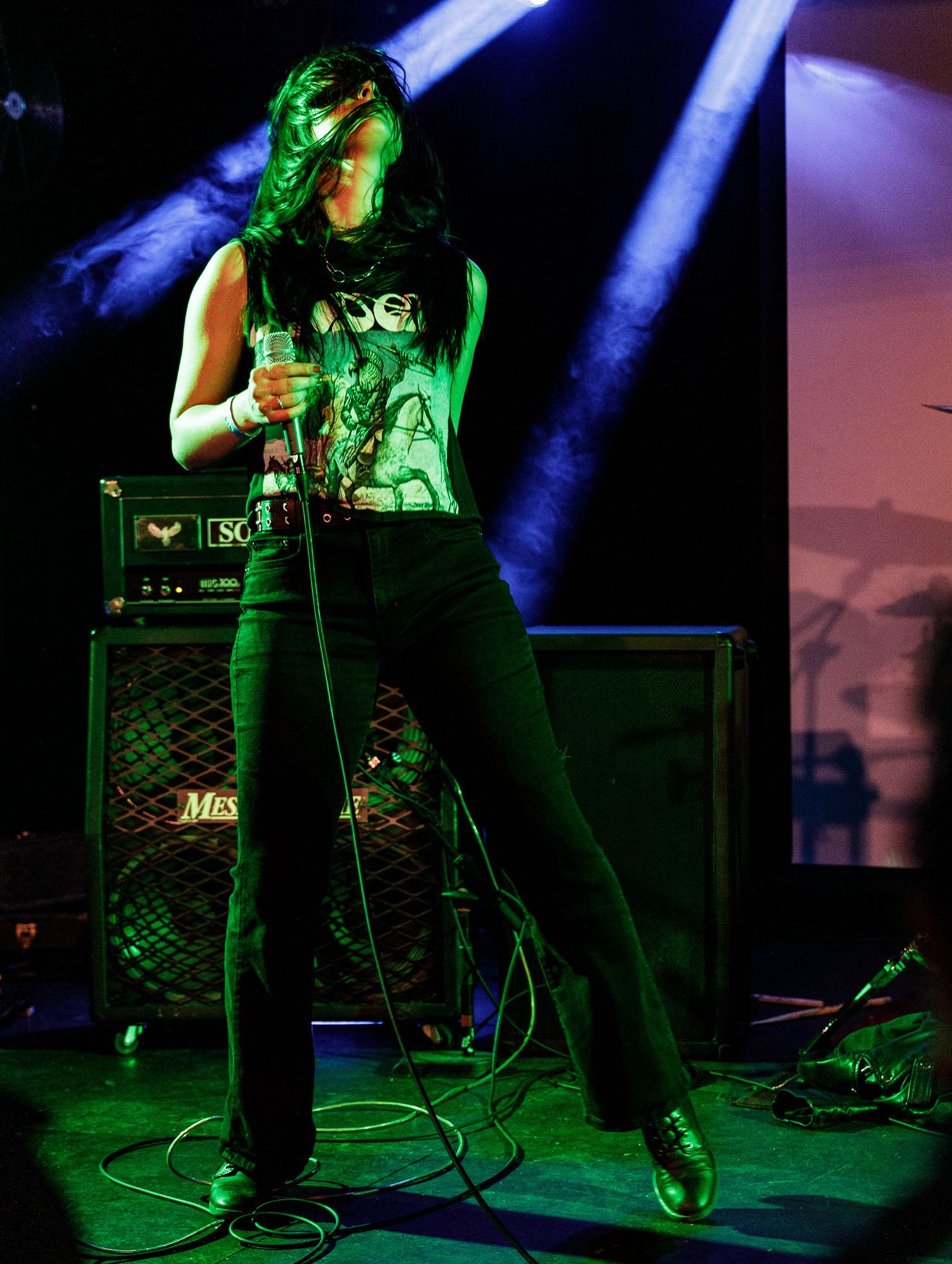 Stage performance with guitar player silhouetted against green and blue stage lighting.
