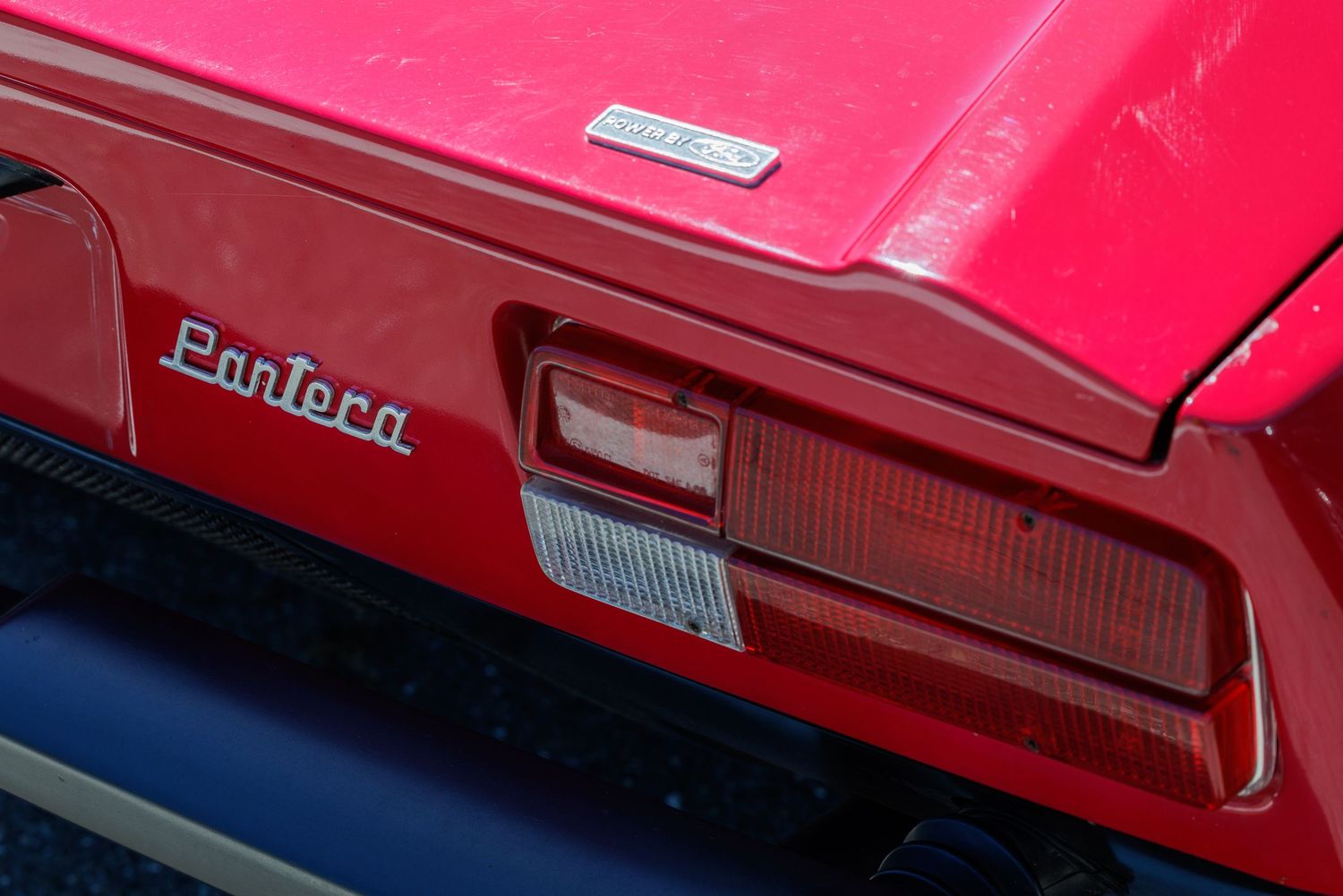Close-up of a red De Tomaso Pantera sports car rear badge and tail light detail.