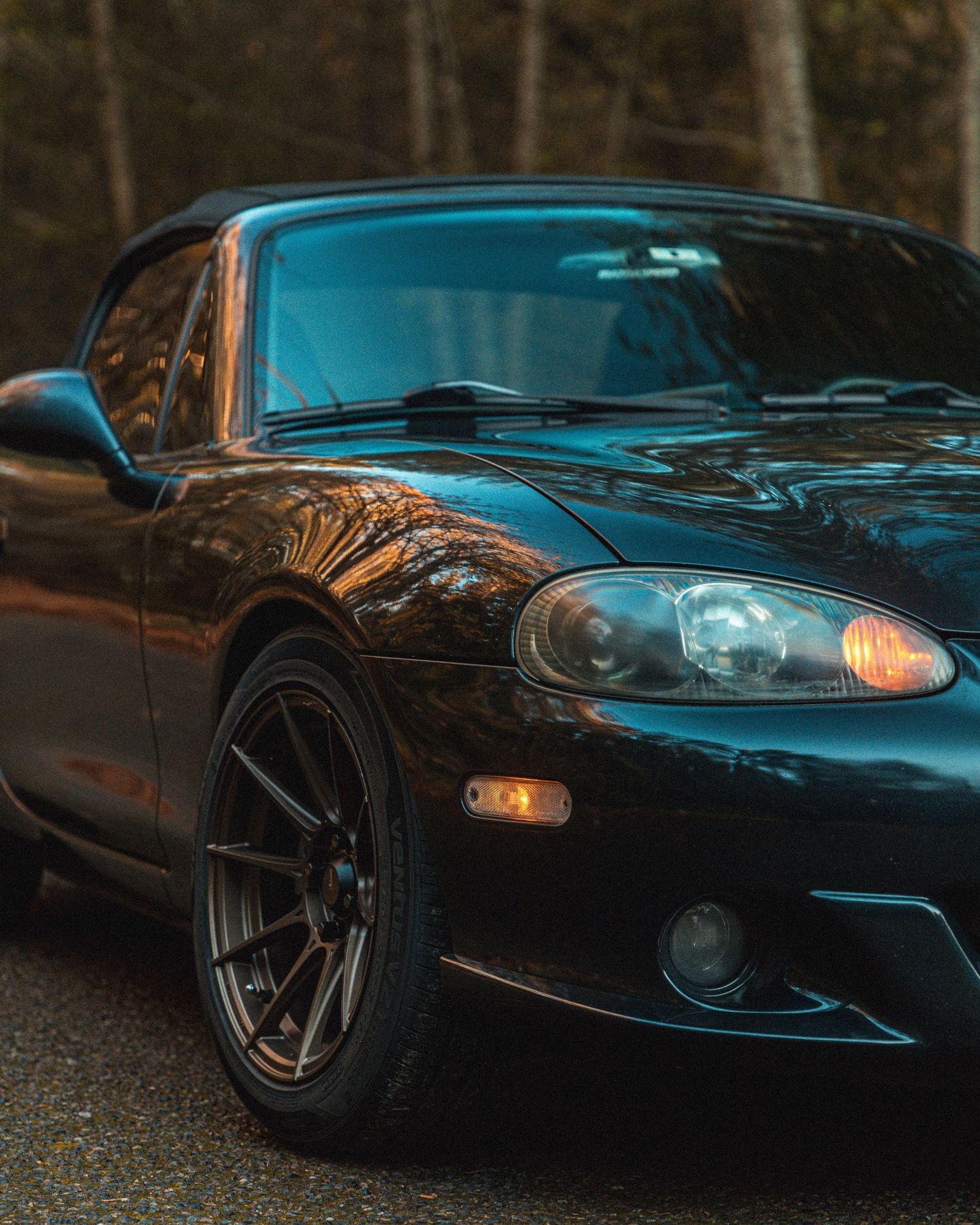Low-light photographs of a black modified sports car with custom wheels and body kit.