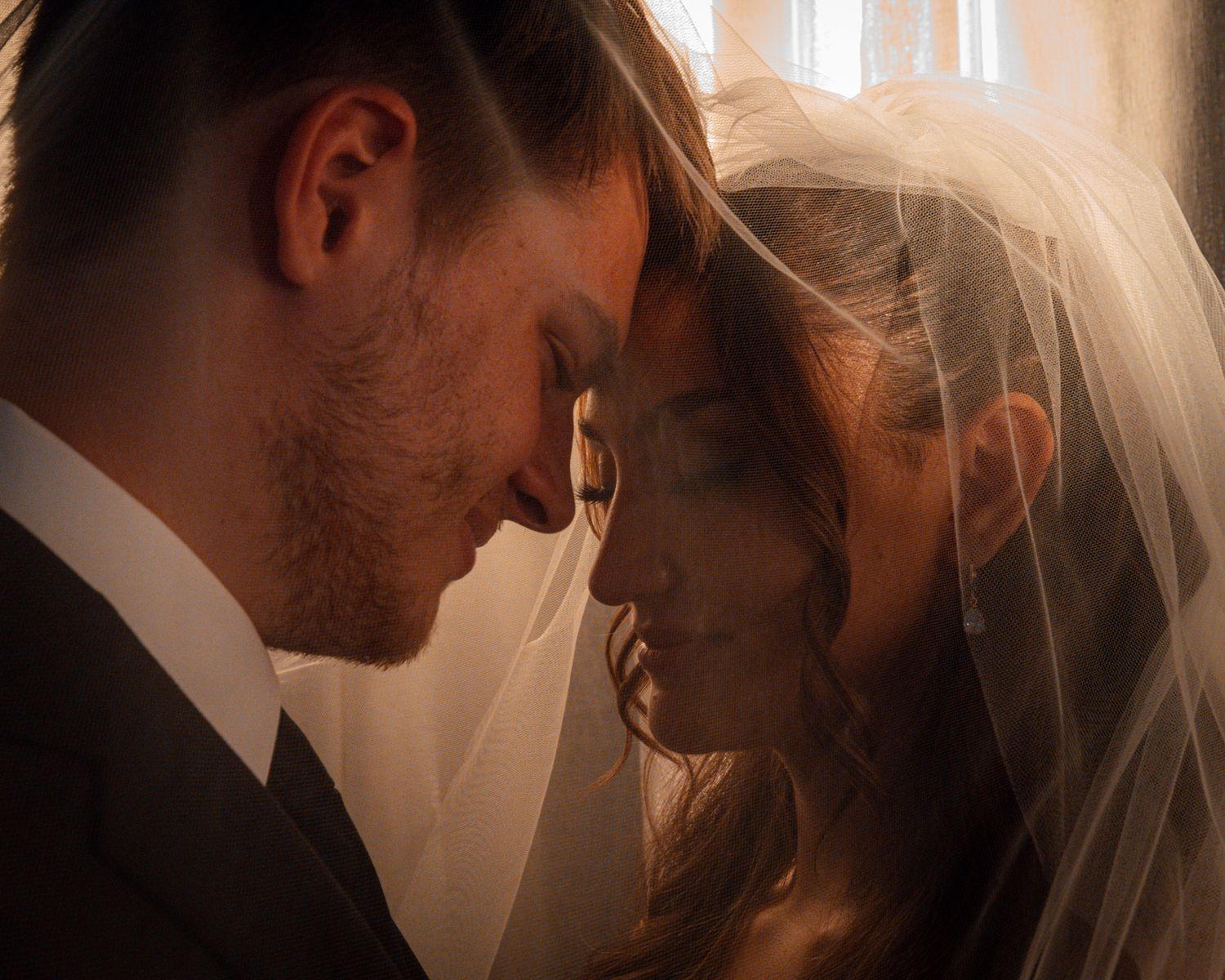 Intimate wedding moment captured in soft, warm lighting.
