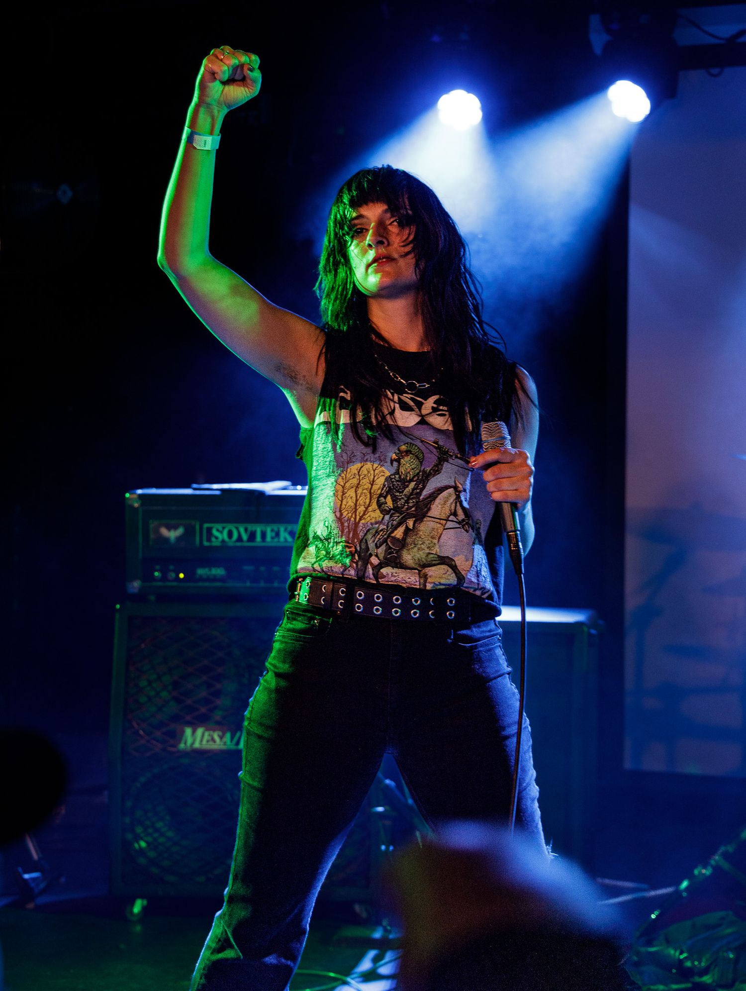 Energetic live music performance with dramatic blue and green stage lighting effects.