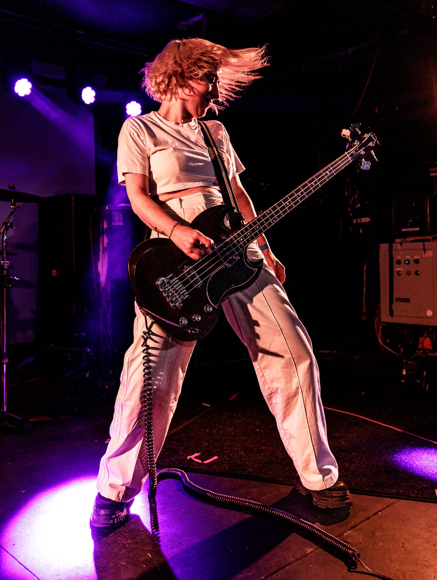 Musicians performing on stage with dramatic low-angle shots under purple spotlights.
