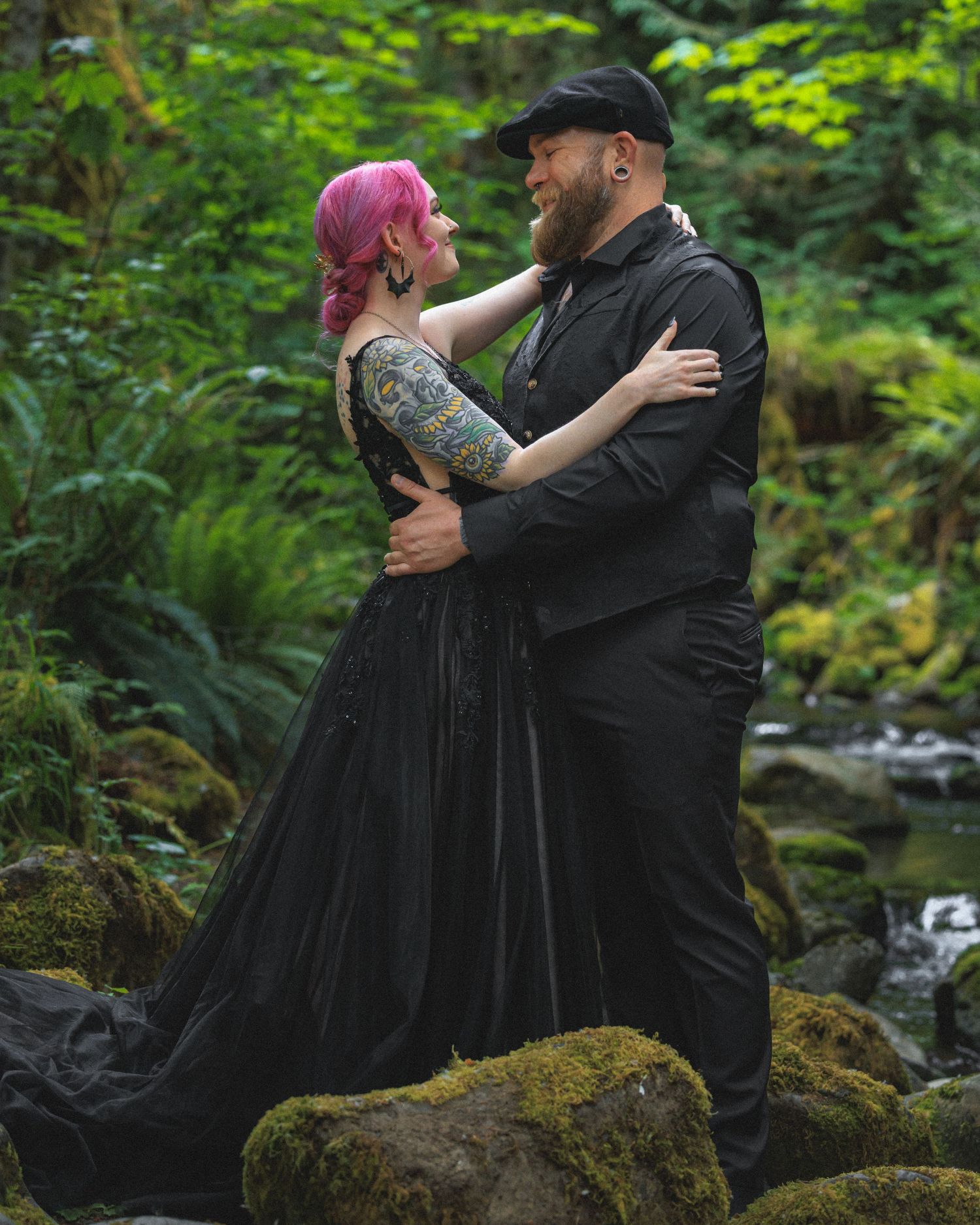 A romantic photoshoot takes place on mossy rocks by a forest stream.