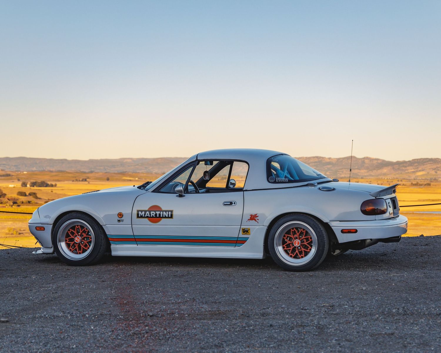 White modified classic car photographed in desert landscape during golden hour.