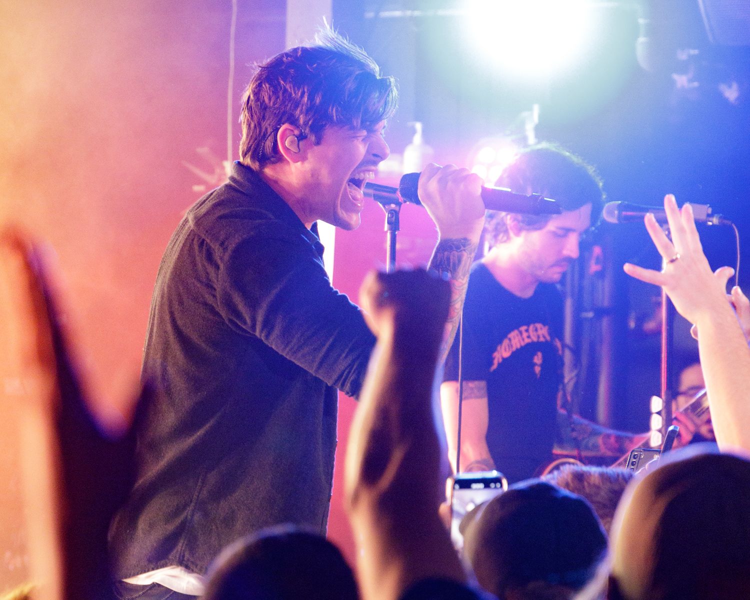Concert crowd silhouettes with bright stage lights creating an atmospheric performance scene.