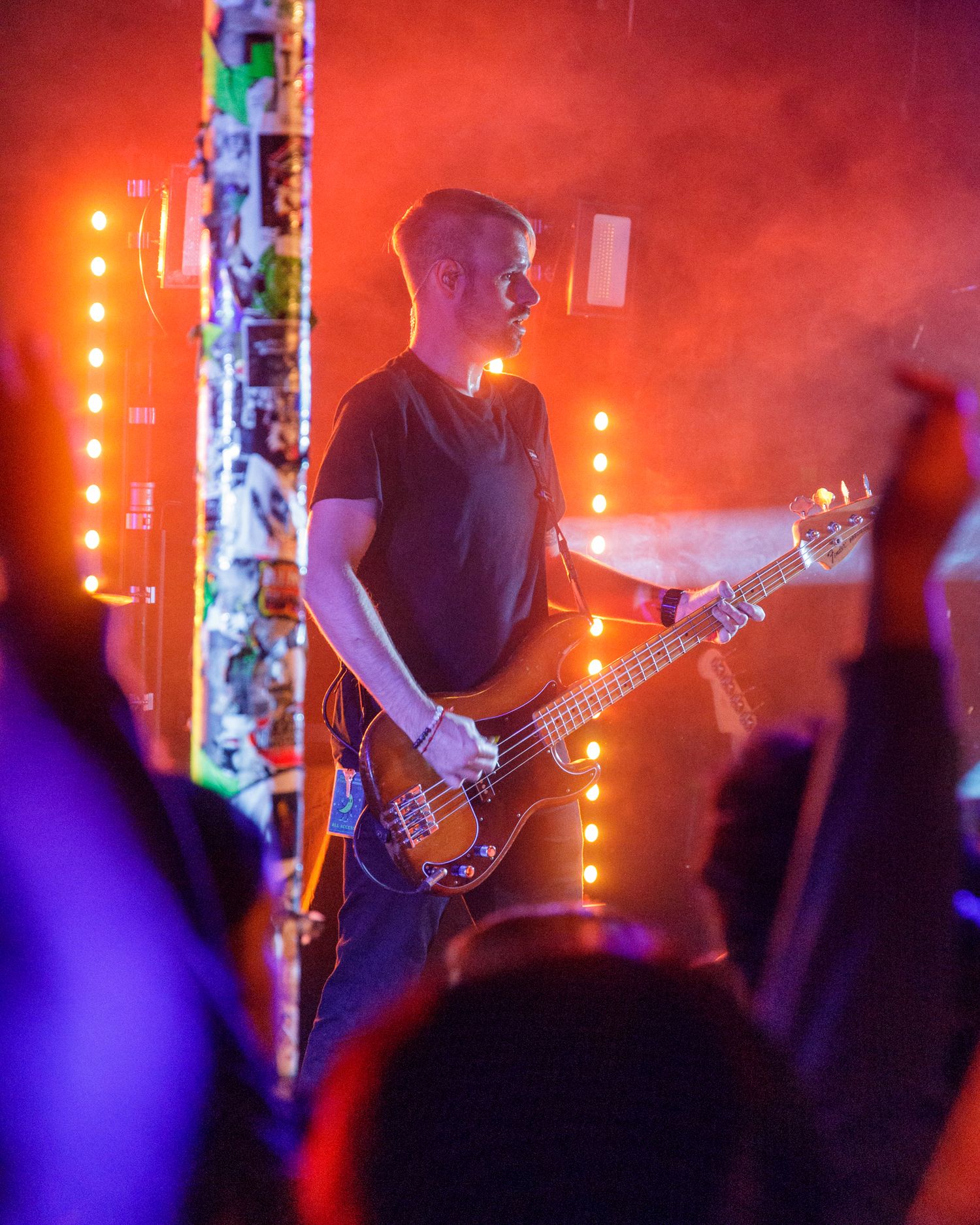 Band members playing instruments under vibrant red and purple stage lighting effects.