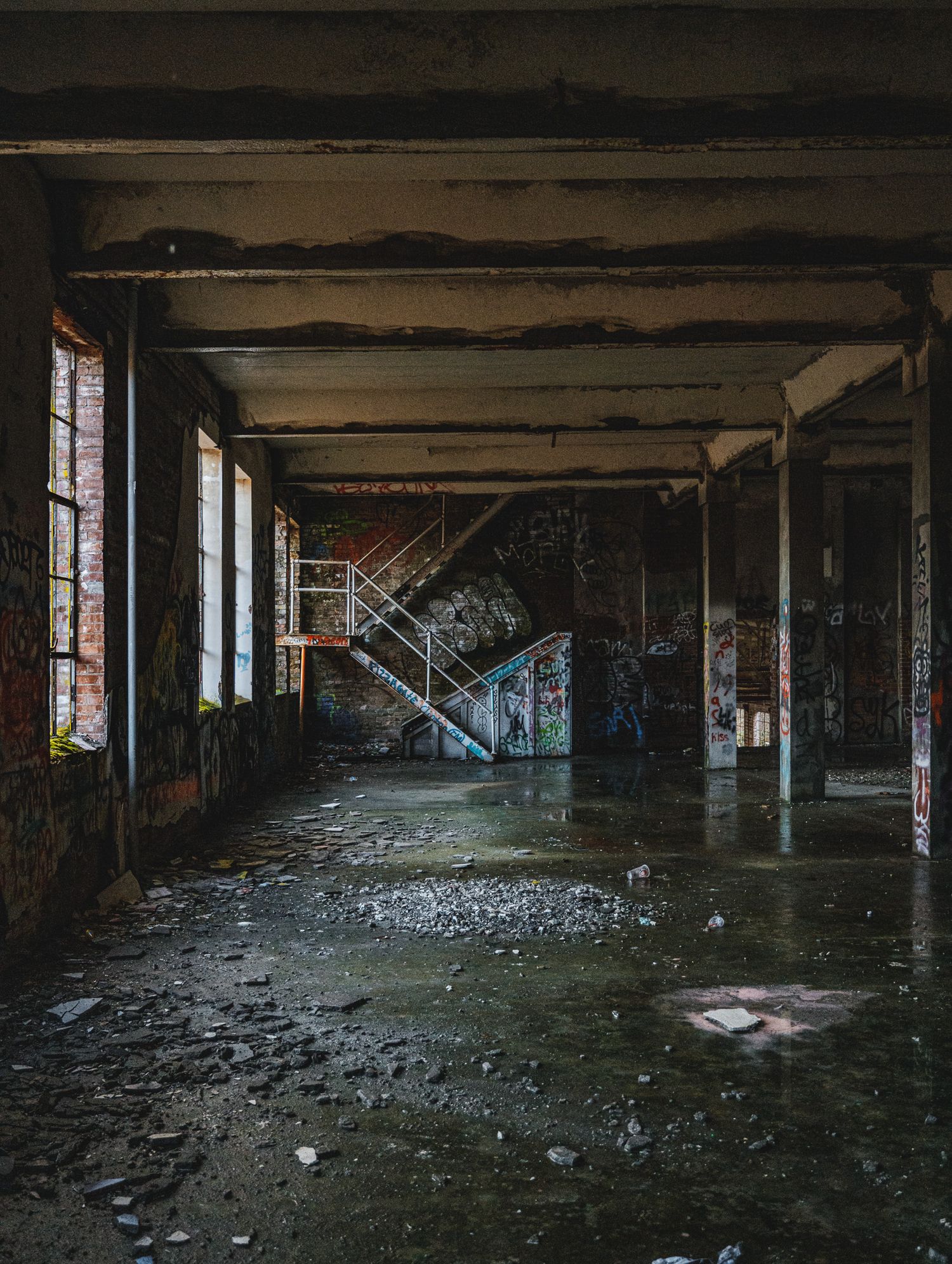 Decaying interior of an abandoned industrial building with debris scattered across the floor.