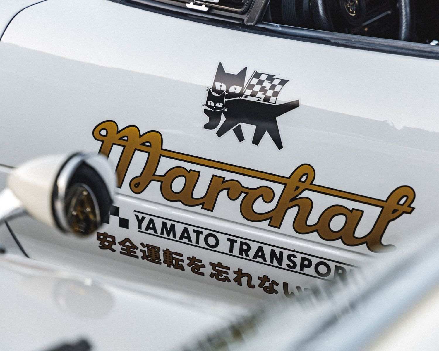 Vintage Japanese text and Marchal branding details on a classic white car.