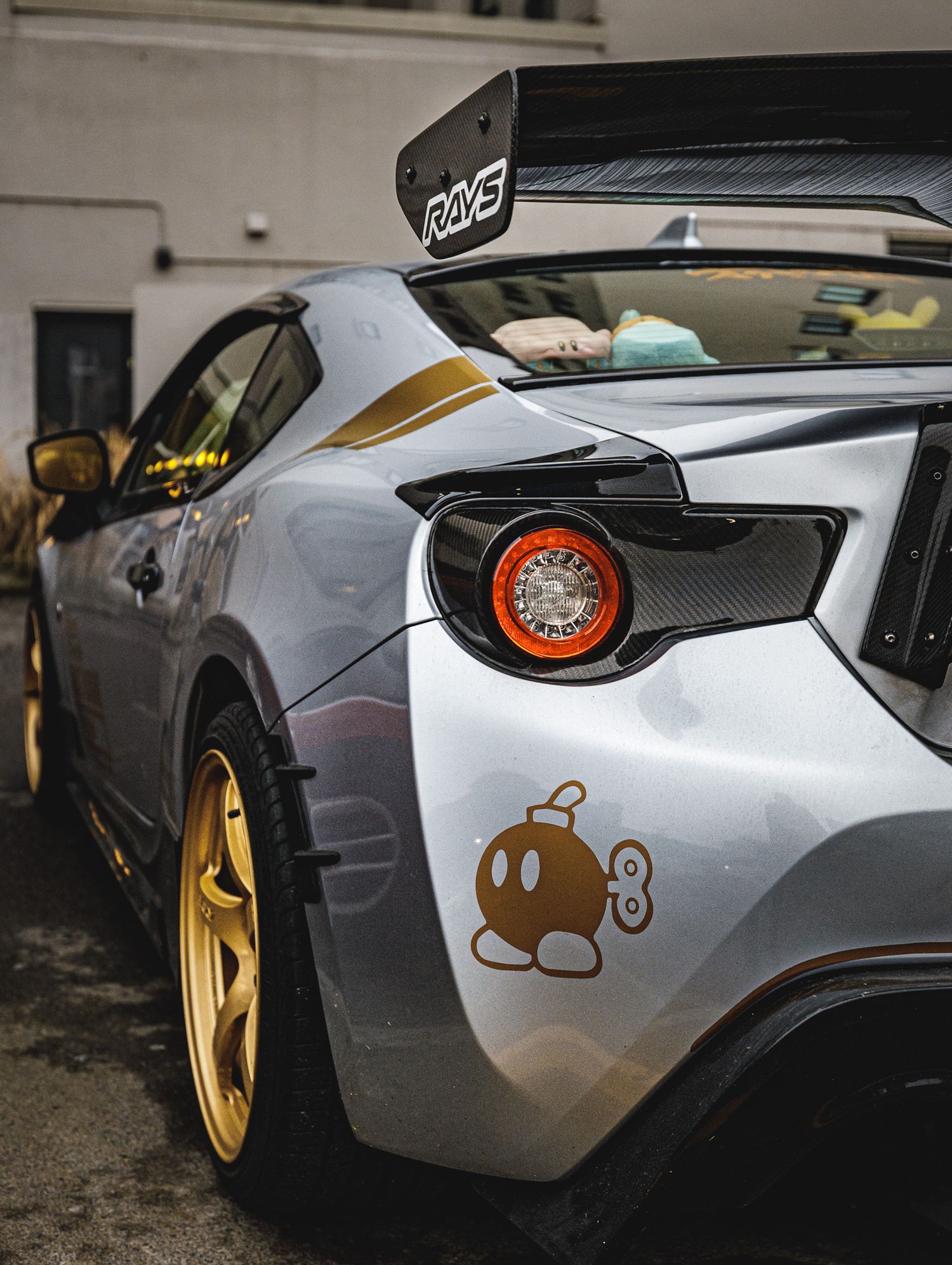 Detail shot of sports car rear section with custom decals and gold accents.