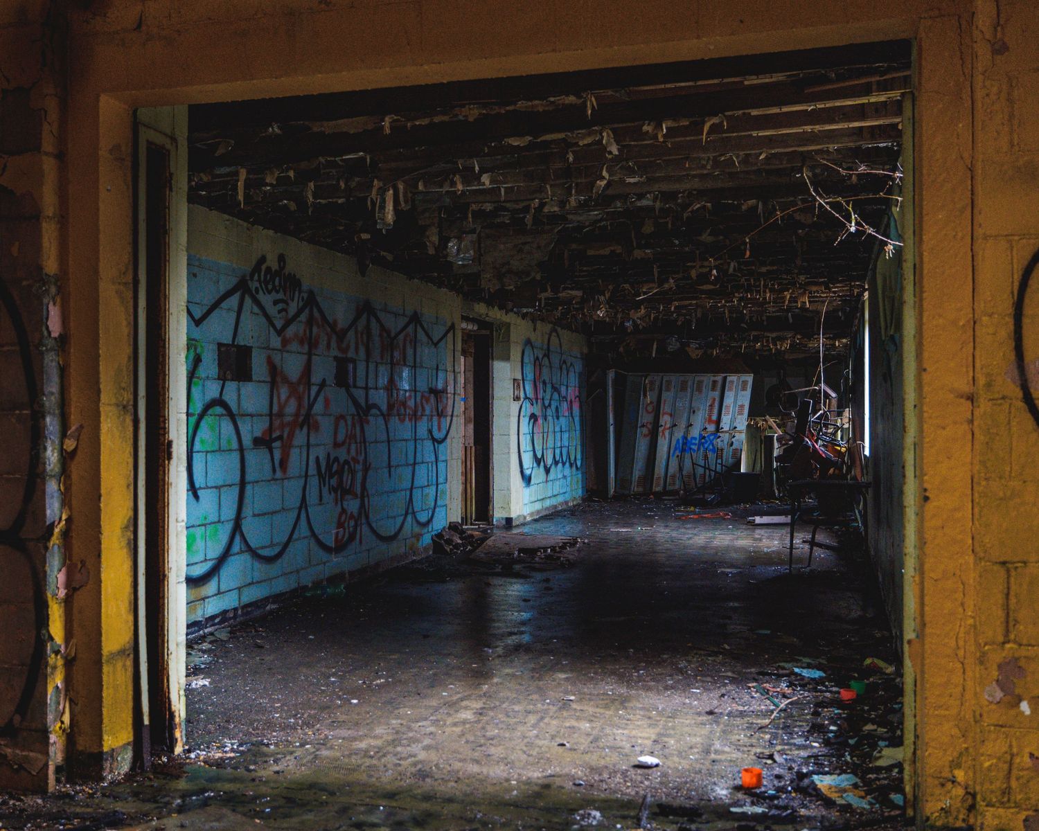 Long abandoned warehouse interior with graffiti covered walls and broken windows.
