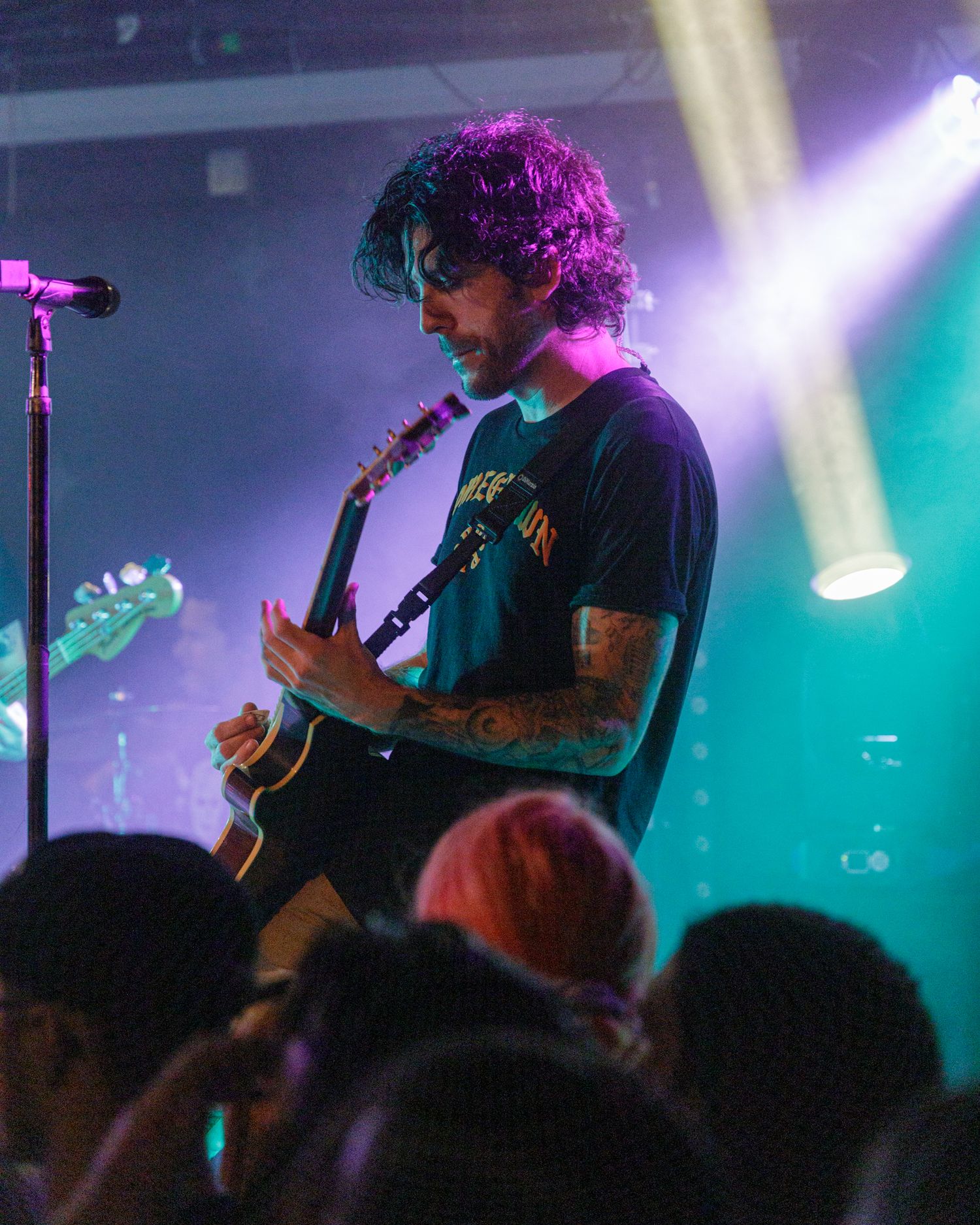 Band performing on stage with teal and purple lighting effects creating atmospheric ambiance.