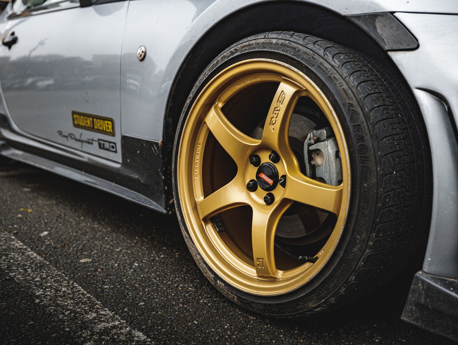 Low angle view of luxury sports car with gold five-spoke wheels and performance tires.