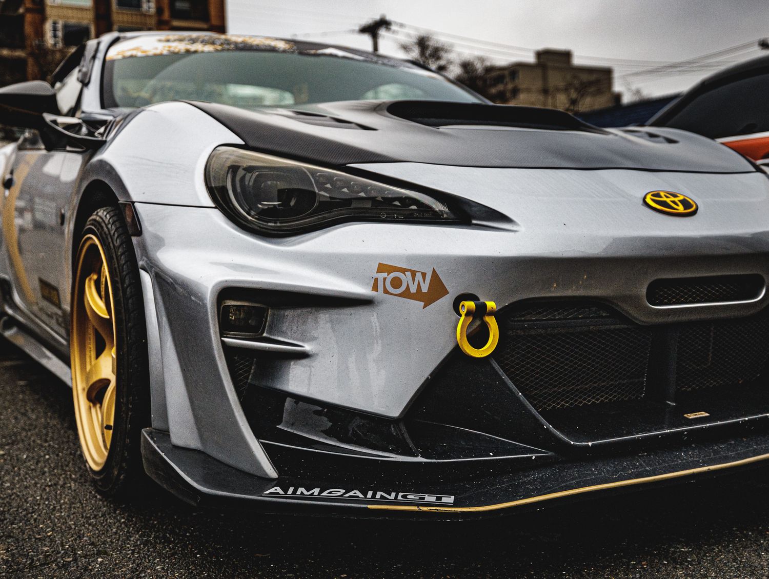 Close-up of white sports car front bumper with gold accents and aerodynamic details.
