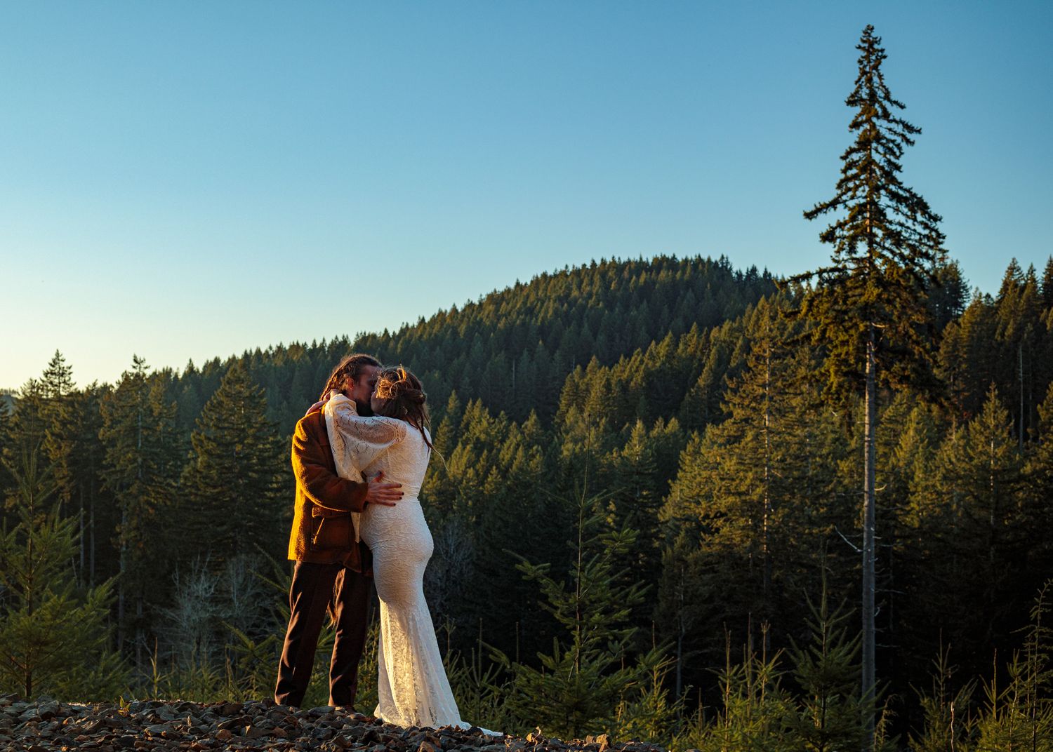 A romantic mountain landscape photoshoot with evergreen trees and blue skies in the background.