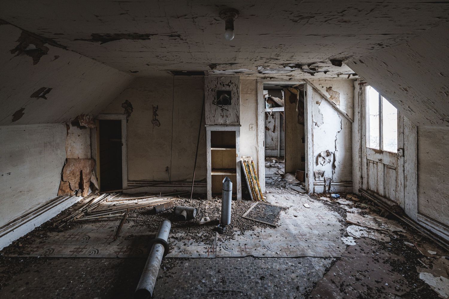Long abandoned corridor with damaged walls and natural light streaming through windows.