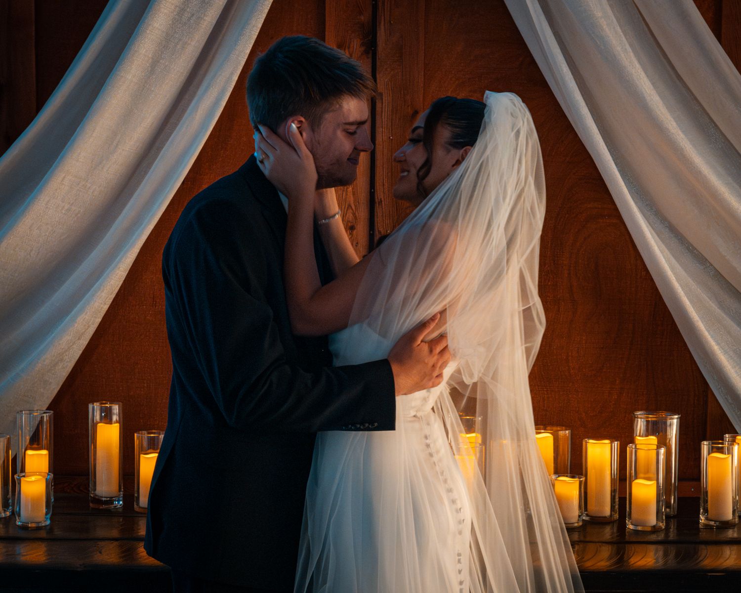 Romantic wedding scene with white drapes and glowing candles creating intimate atmosphere.