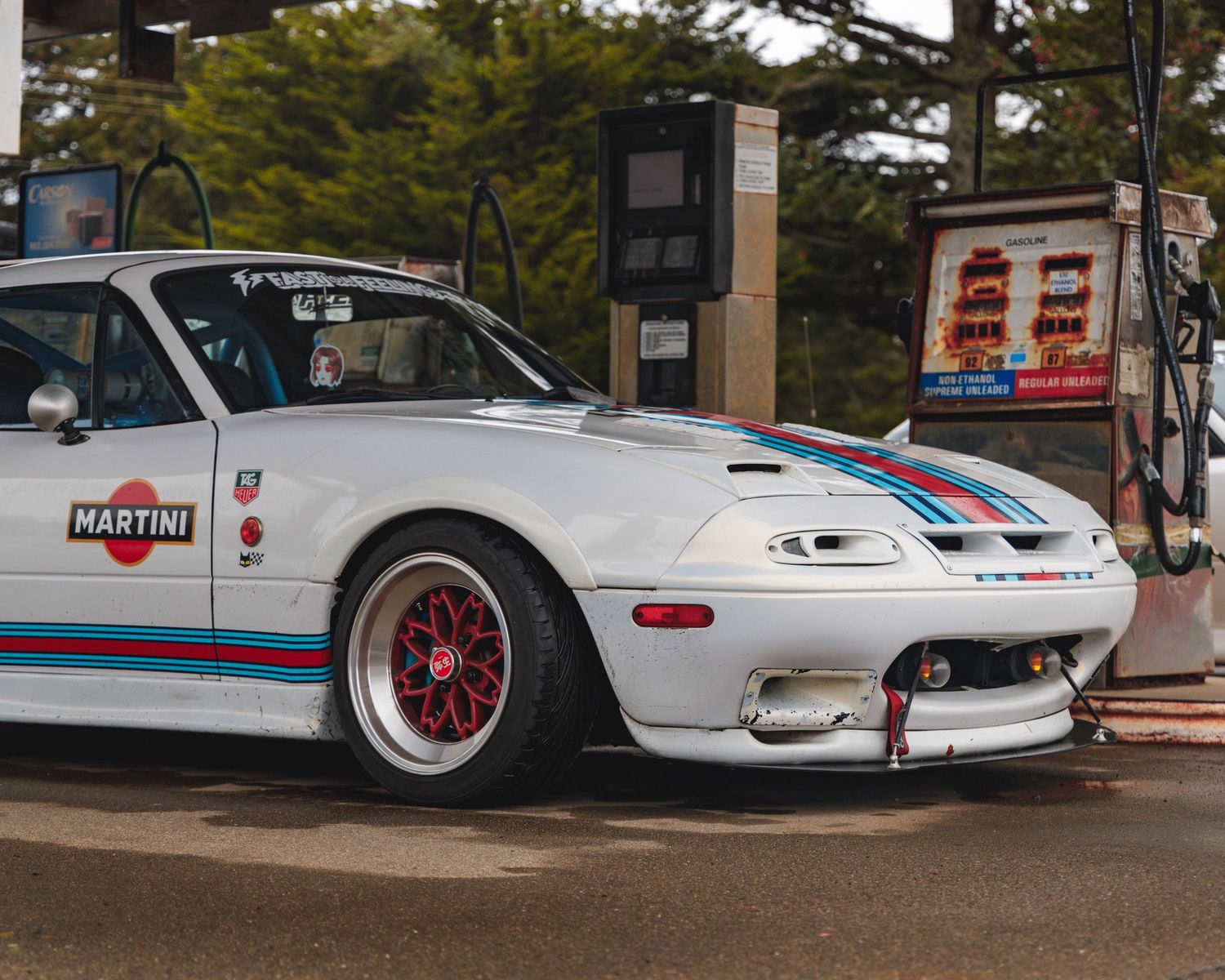 Row of lowered white sports cars with Martini racing livery and custom wheels.
