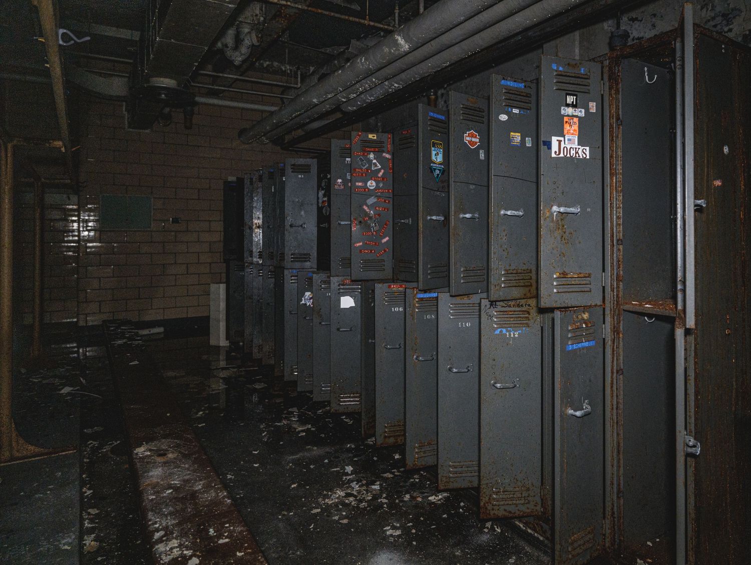 Row of electrical panels and utility boxes line dark industrial basement hallway.