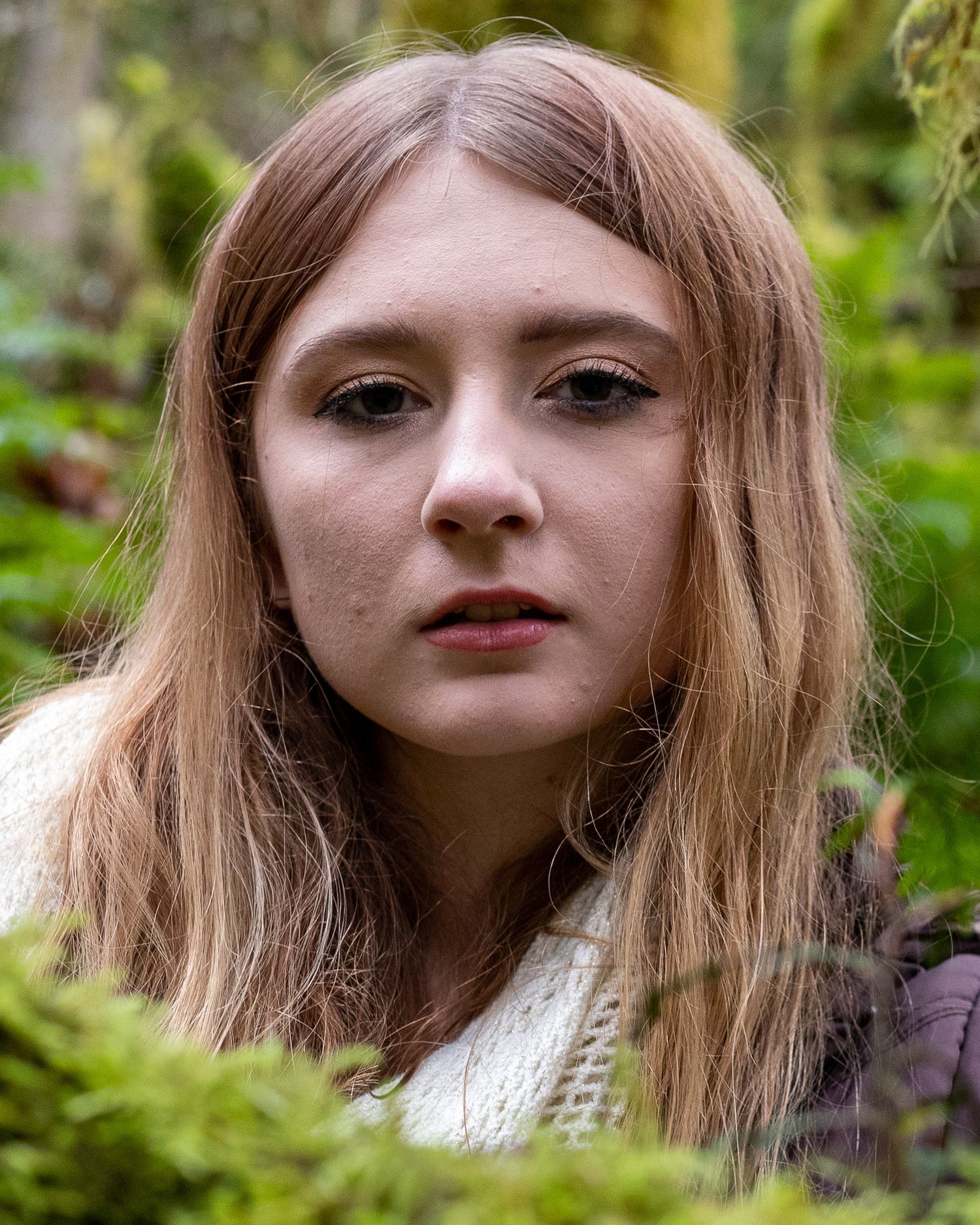 Natural outdoor portraits among green foliage with soft lighting and flowing hair.