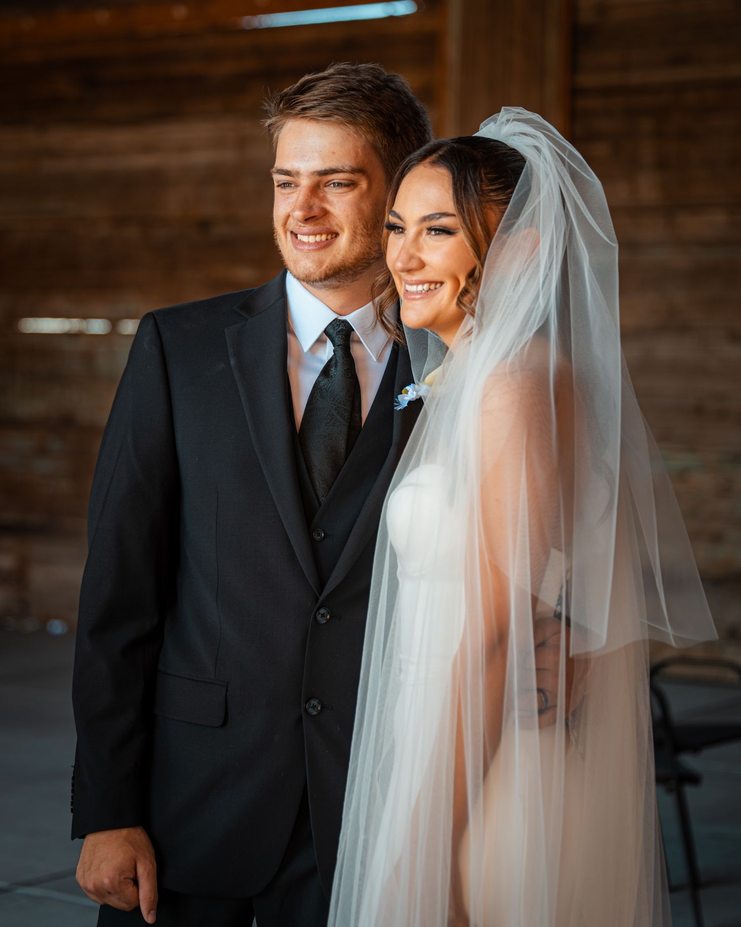 Candid wedding portraits showing tender moments between the newlyweds in a rustic indoor setting.