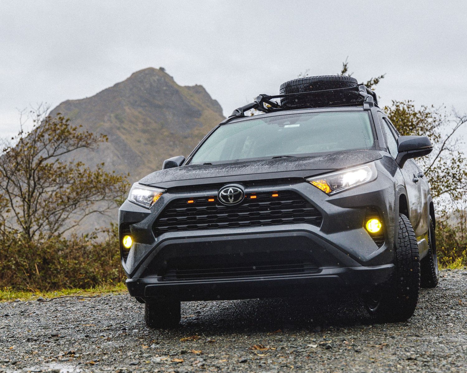 Black Toyota RAV4 or similar SUV shown in dramatic low angle shots against mountain backdrop.