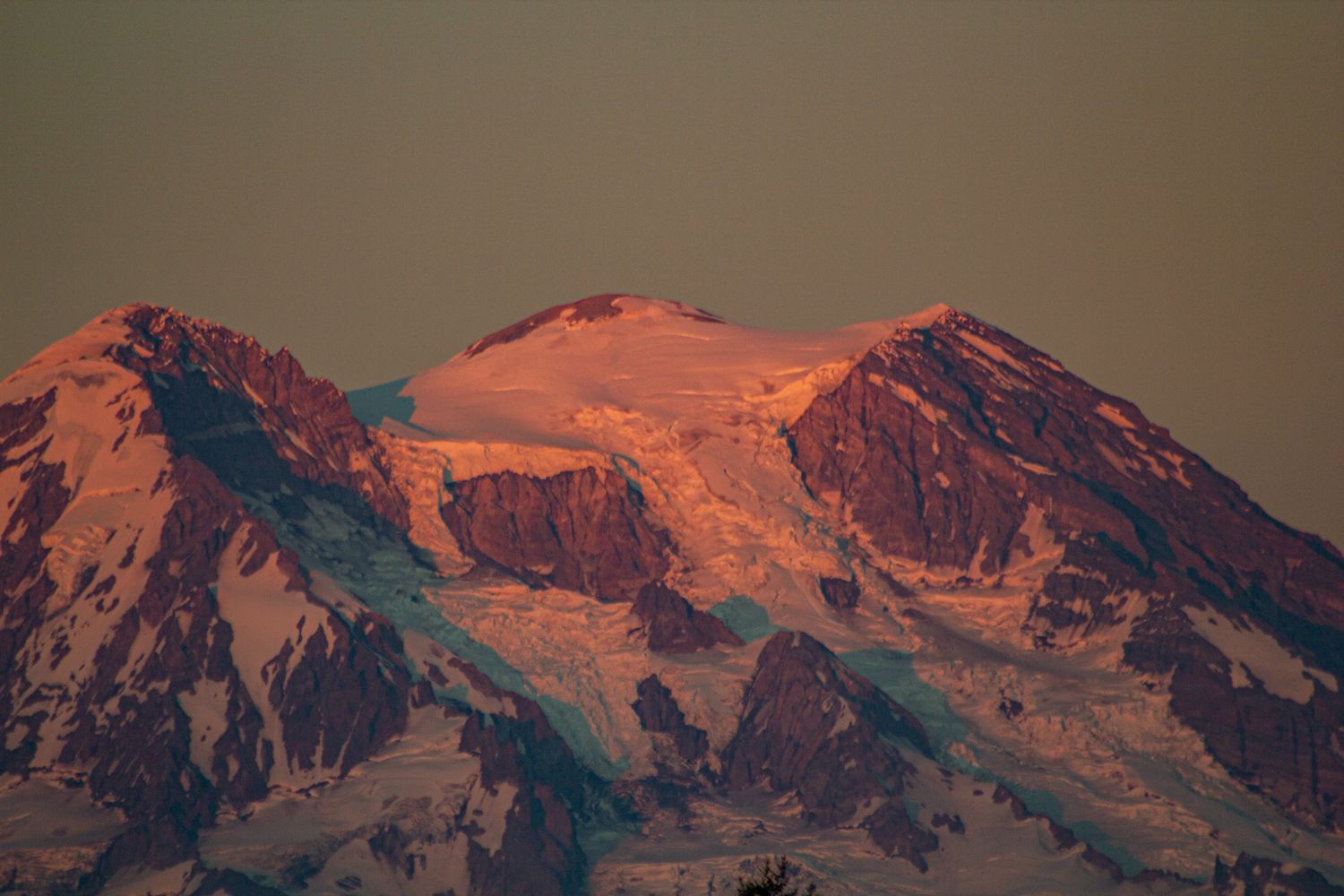 Sunset light illuminates snowy mountain peaks with warm orange alpenglow.