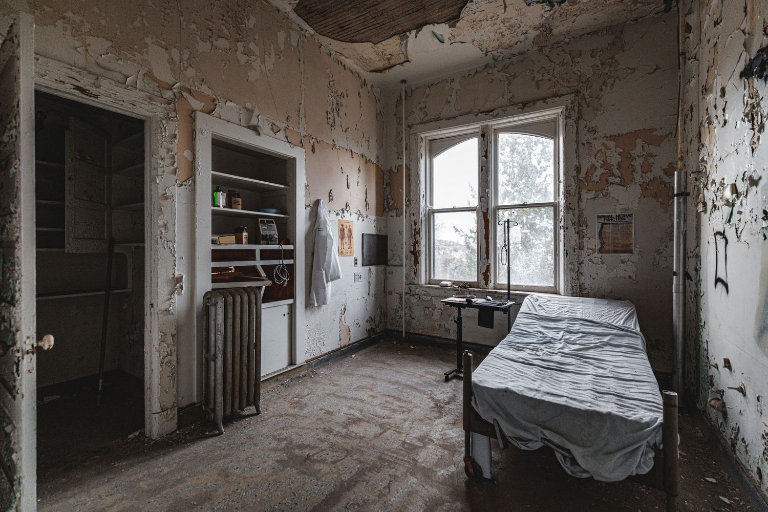 Deteriorating hallway with exposed brick walls and covered furniture in natural light.