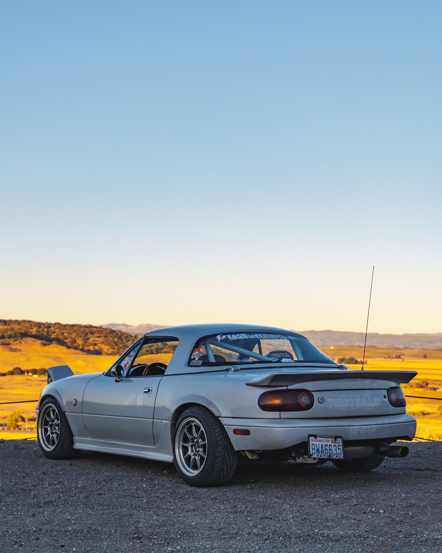 Side views of a modified white classic car against desert backdrop at sunset.