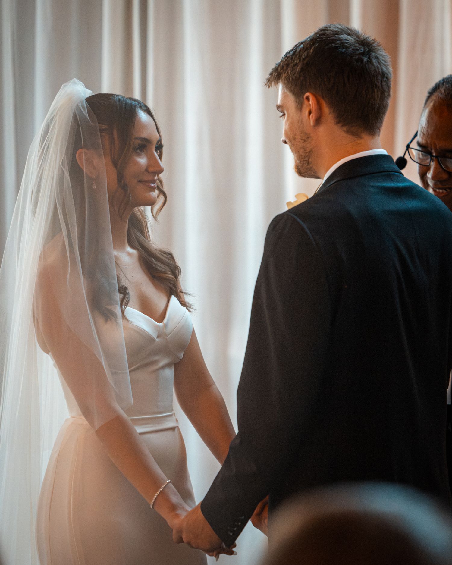Wedding ceremony captured in soft, romantic lighting with flowing white veil.
