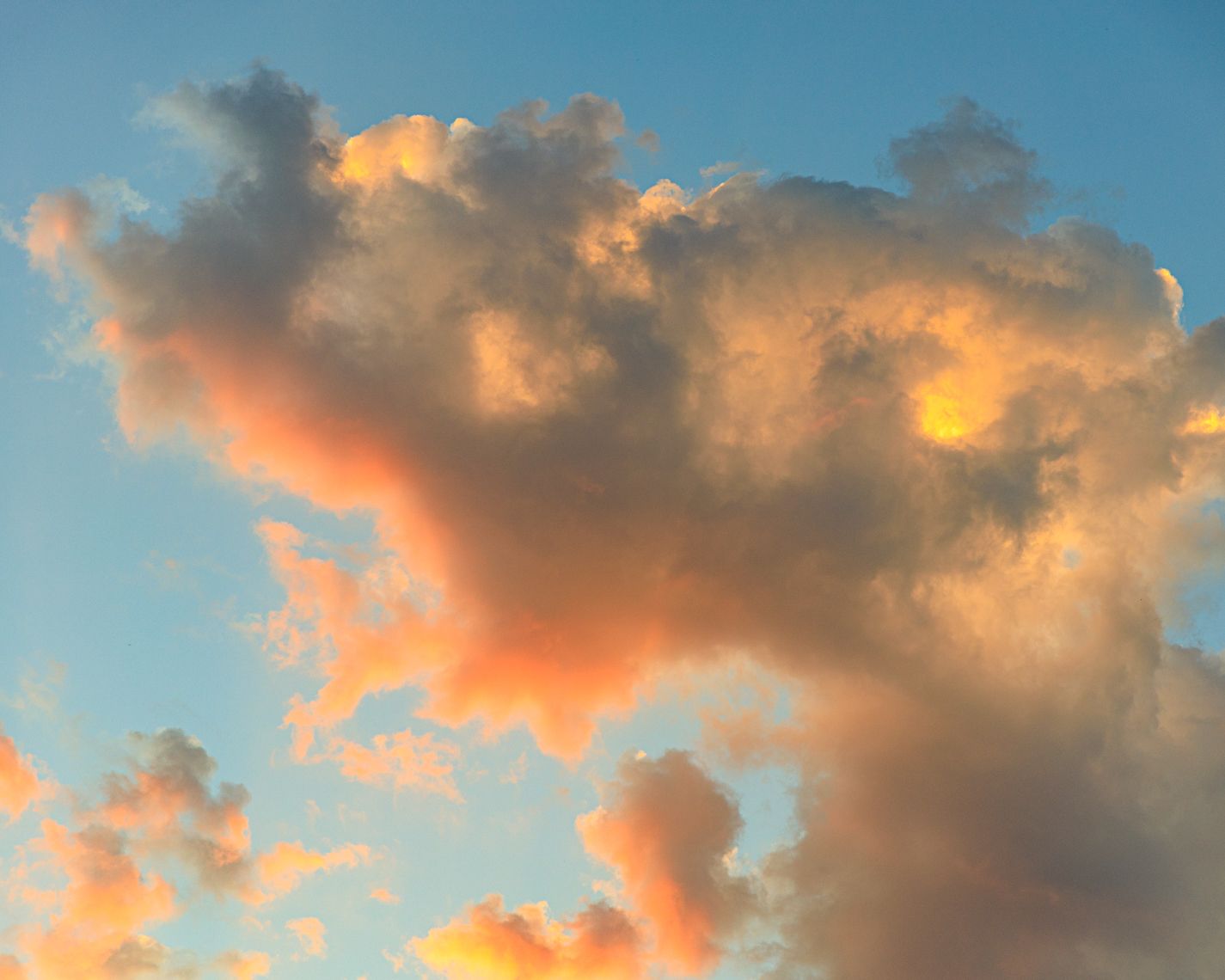 Panoramic view of a vibrant sunset sky with golden clouds against deep blue backdrop.