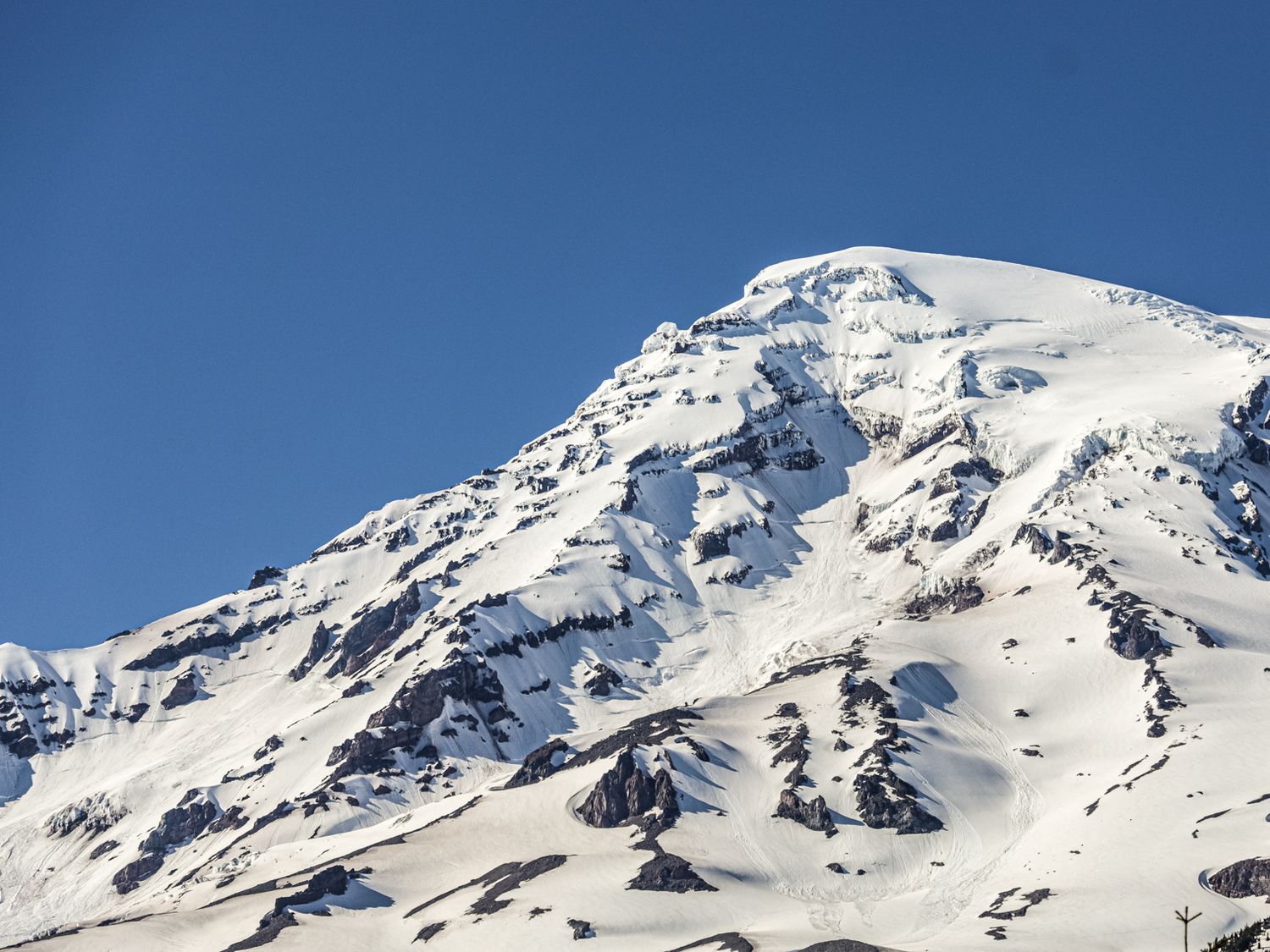 Snow-covered mountain peaks against clear blue sky in winter landscape.