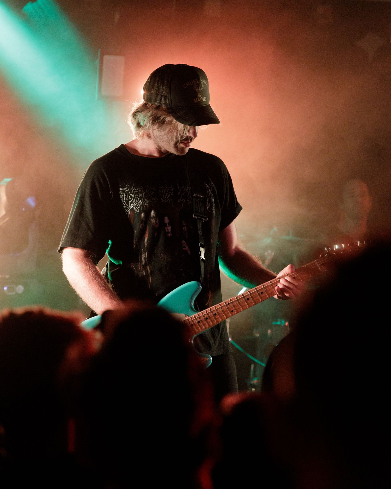 Silhouetted musicians performing against warm-colored stage lighting and fog effects.