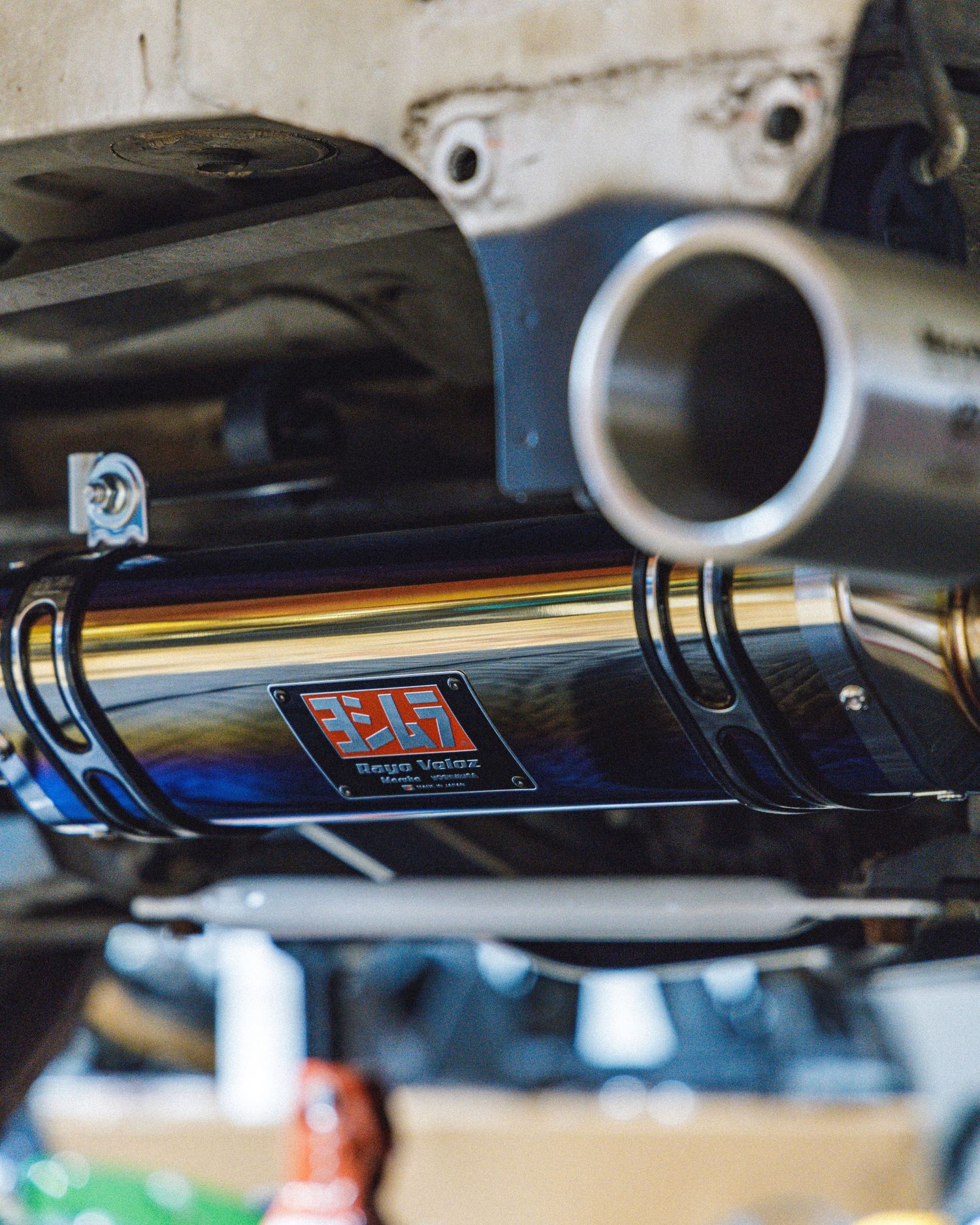Underneath view of a performance car showing a black exhaust system installation.